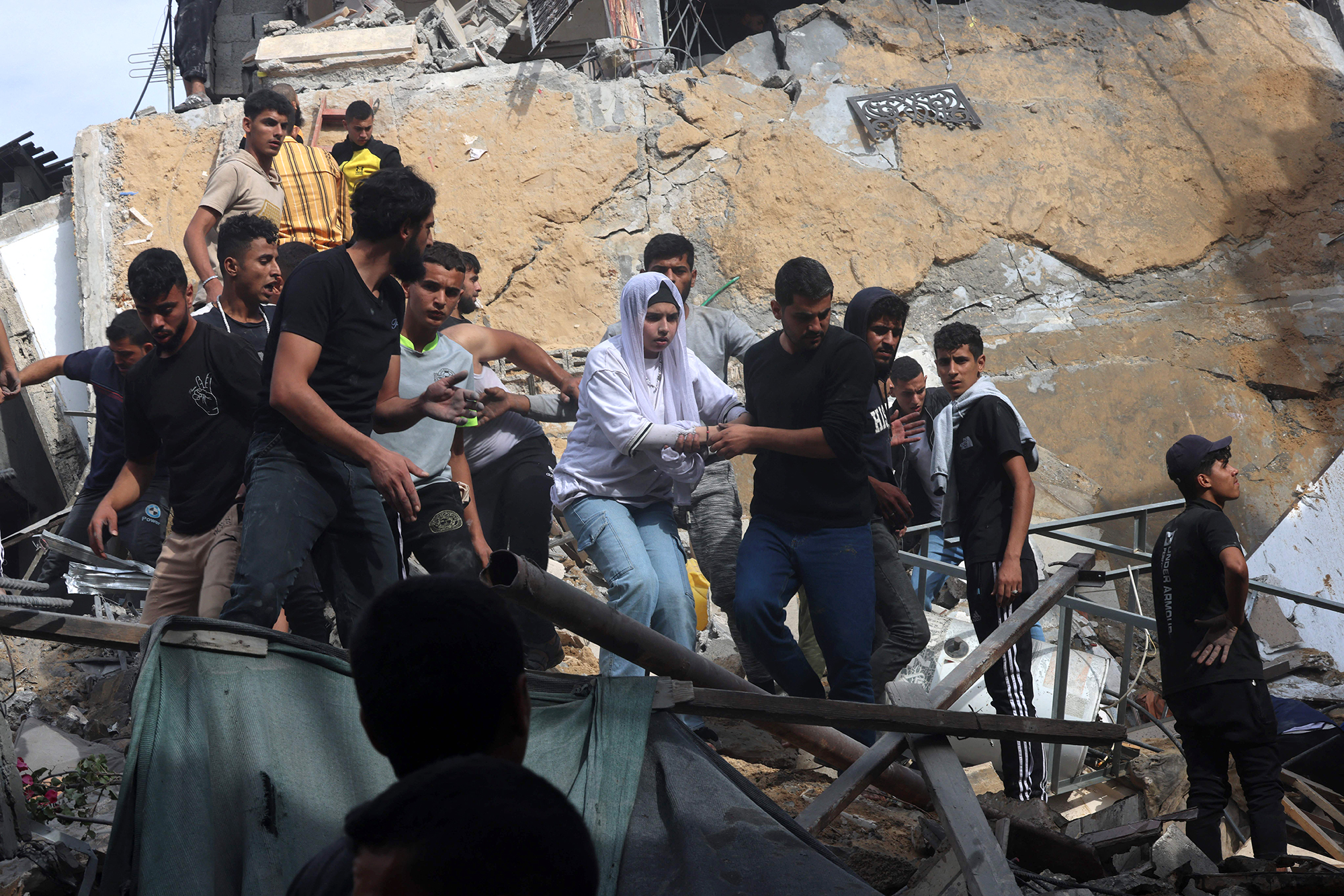 A woman is helped down from a building destroyed during Israeli attack in Rafah, Gaza, on November 11. 