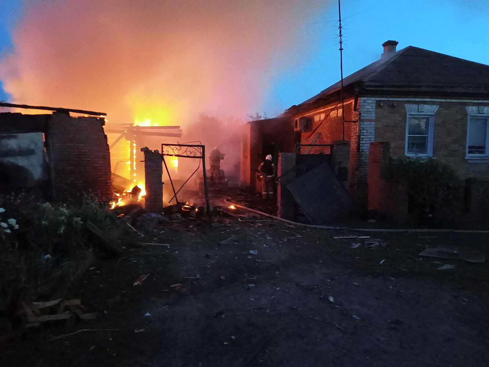 Firefighters work at a house on fire following a shelling in the village of Sobolevka, Belgorod region, Russia.