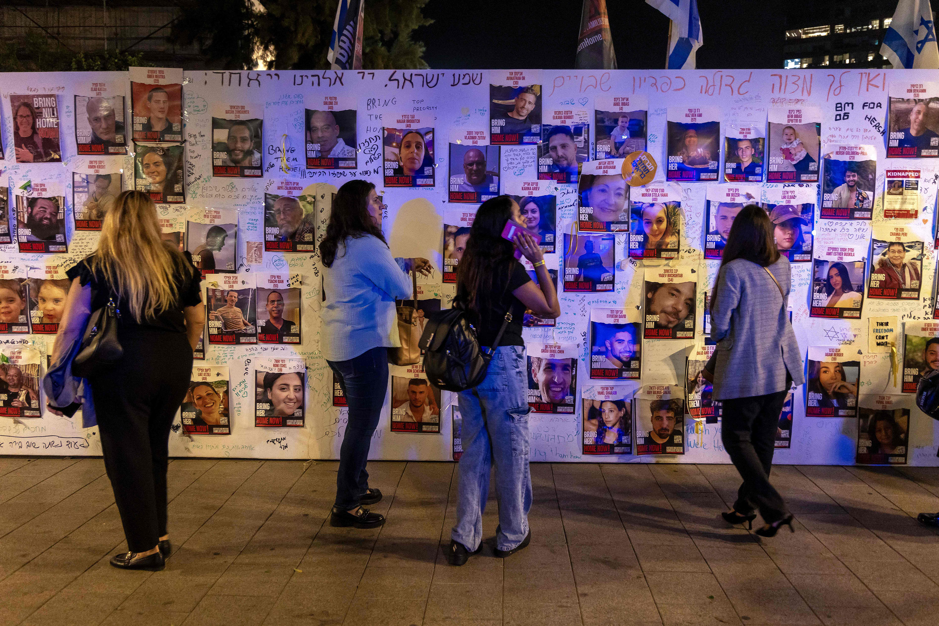 Mensen staan ​​maandag voor een muur met posters van vermiste of ontvoerde mensen in Tel Aviv, Israël.