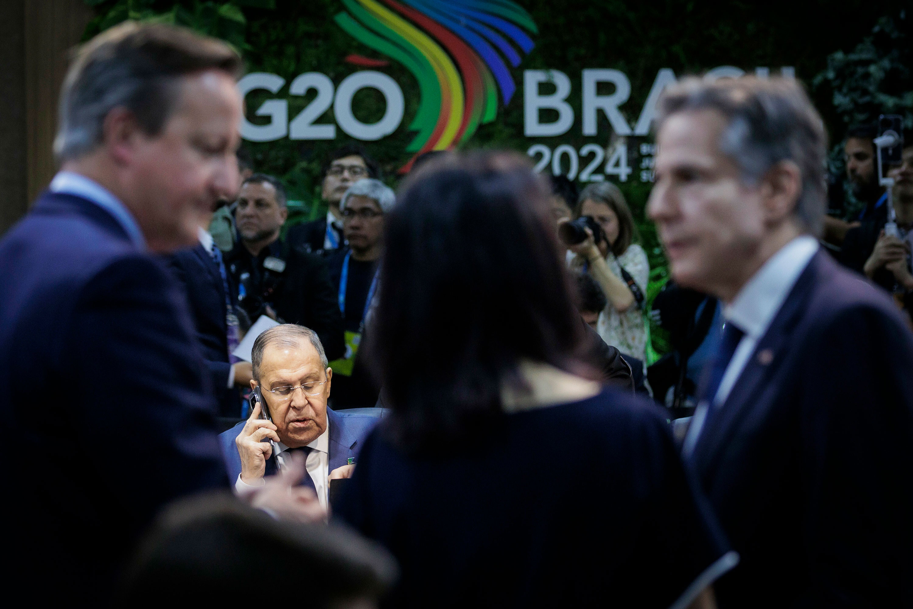 Russian Foreign Minister Sergey Lavrov talks on the phone during the G20 Foreign Ministers meeting Wednesday in Rio de Janeiro. In the foreground, Britain's Foreign Secretary David Cameron, German Foreign Minister Annalena Baerbock and US Secretary of State Antony Blinken speak to each other. 