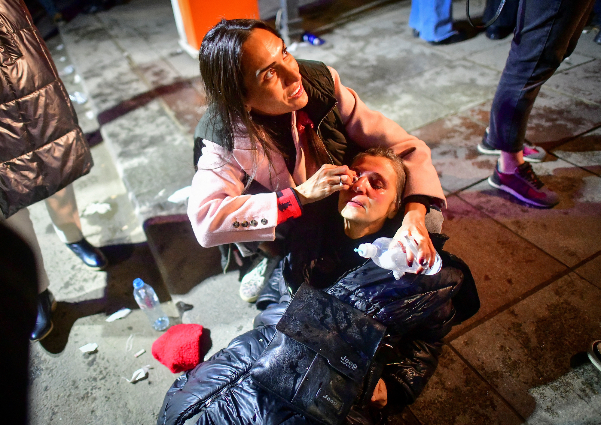 Una donna colpita dai gas lacrimogeni riceve assistenza medica per strada.