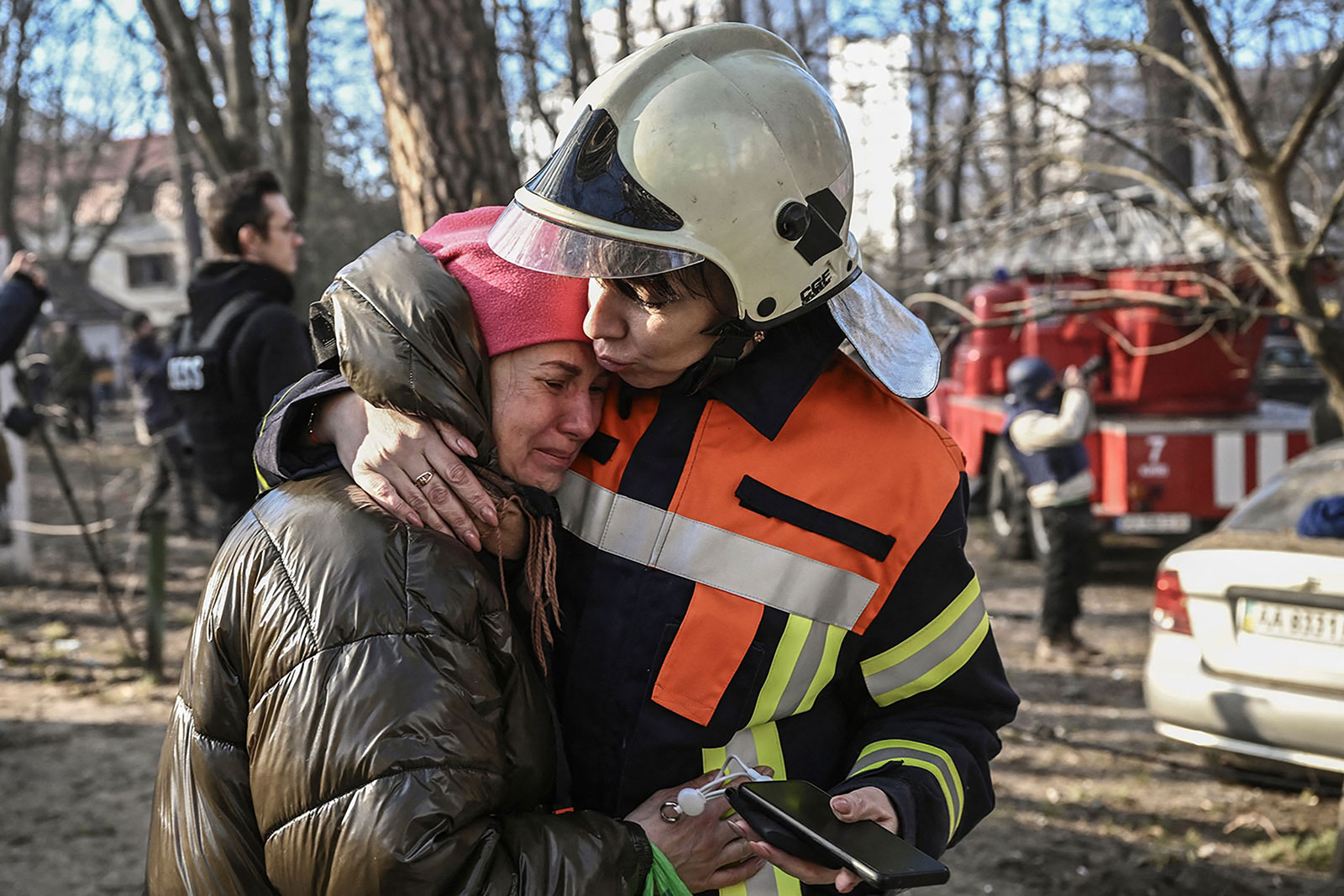 An evacuated resident is comforted by Svitlana Vodolaga, spokesperson for State Emergency Services of Ukraine outside a burning apartment building in Kyiv on March 15, after strikes on residential areas killed at least two people.