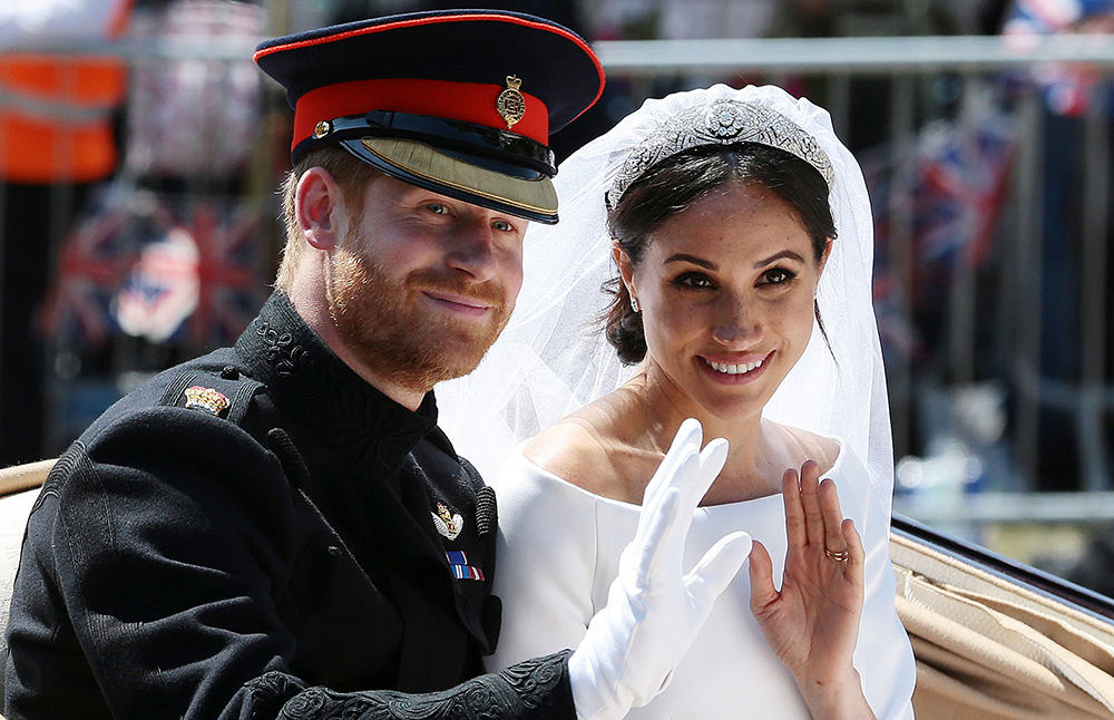 Britain's Prince Harry, Duke of Sussex and his wife Meghan, Duchess of Sussex wave as they head back towards Windsor Castle after their wedding ceremony on May 19. 