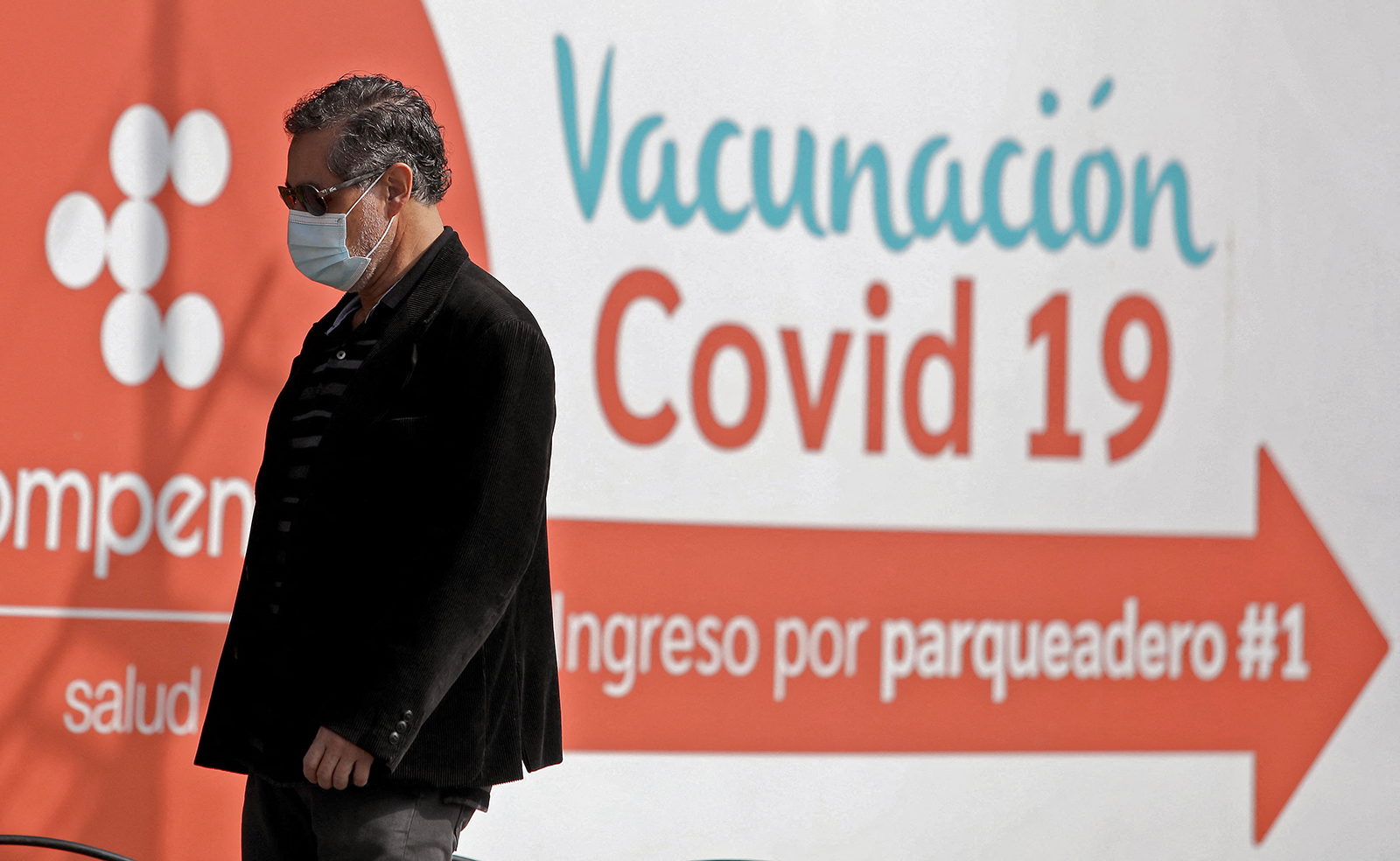 A man walks past a sign indicating a vaccination point against Covid-19 in Bogota, on December 21. Colombian health authorities detected the first three cases of the Omicron variant of Covid-19 in passengers who arrived from the US and Spain. 