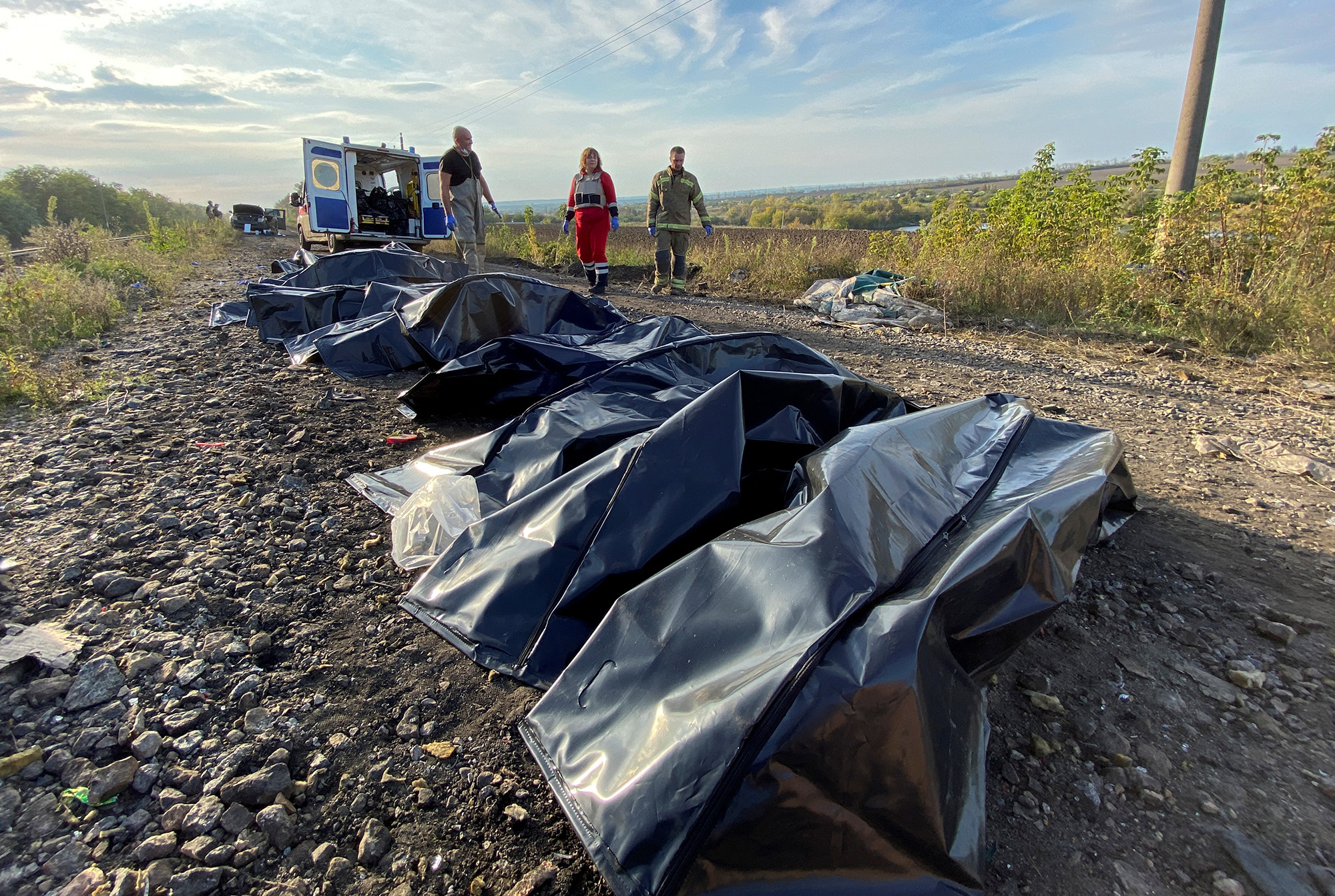 Volunteers stand next to the bodies of members of a civilian convoy killed near the village of Kurylivka in Kharkiv region, Ukraine, on October 1.