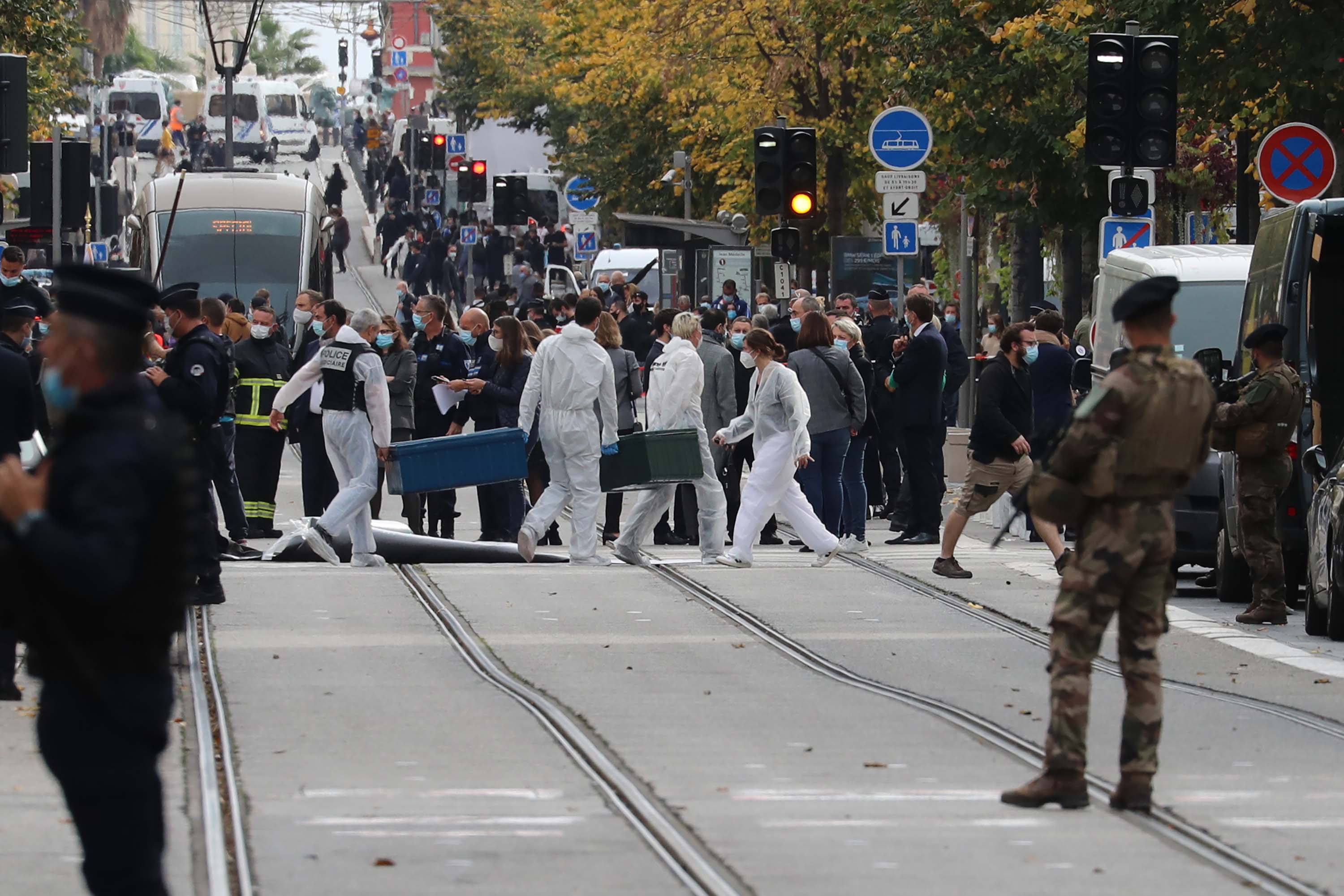 Forensics officers work at the site of a knife attack as French soldiers stand guard in Nice.