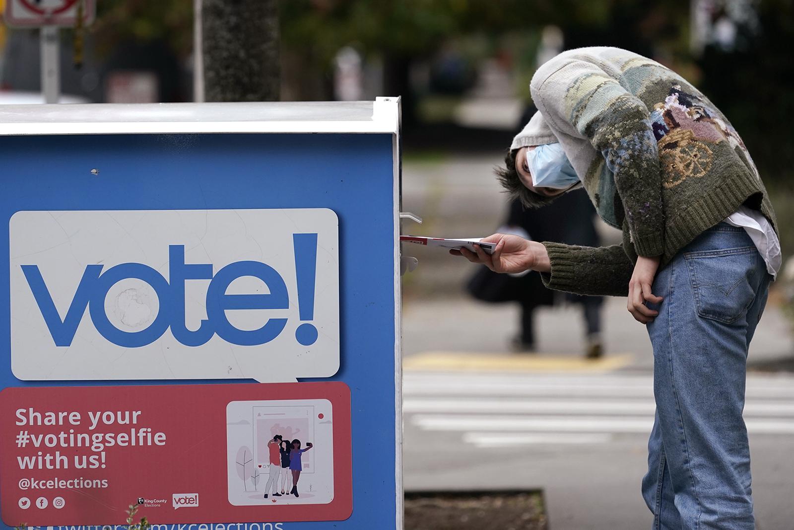 A voter turns sideways as he eyes the opening of a ballot drop box before placing his ballot inside it Wednesday, October 28, in Seattle. 