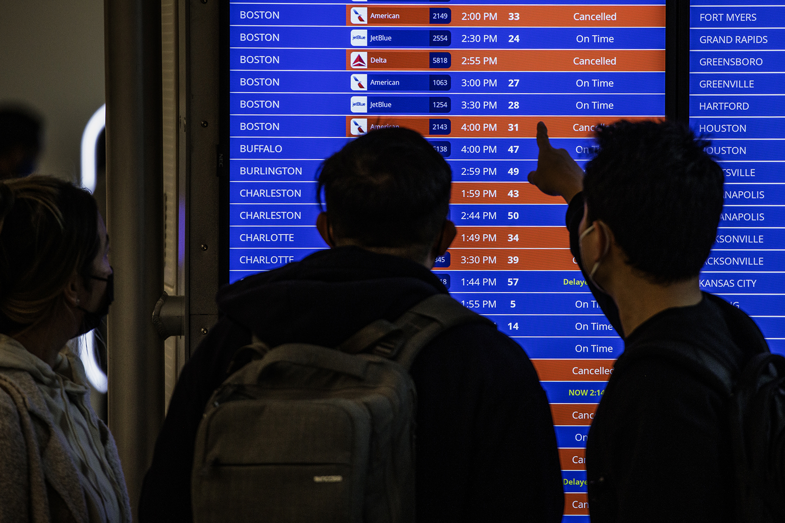 Travelers look at flight timetables displayed on a departure board at Ronald Reagan National Airport (DCA) in Arlington, Virginia, on Sunday, January 16.