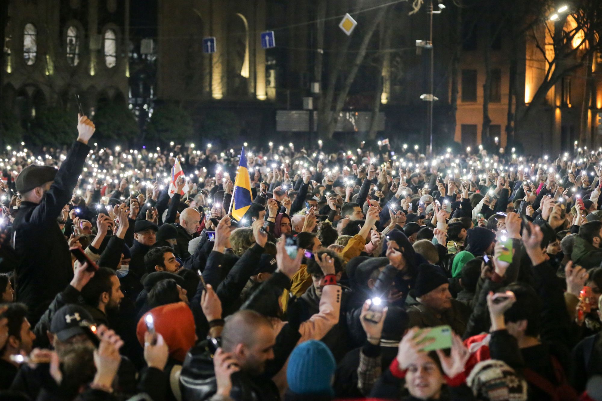 Protesters show cellphone flashlights as they demonstrate in front of the Georgian parliament.