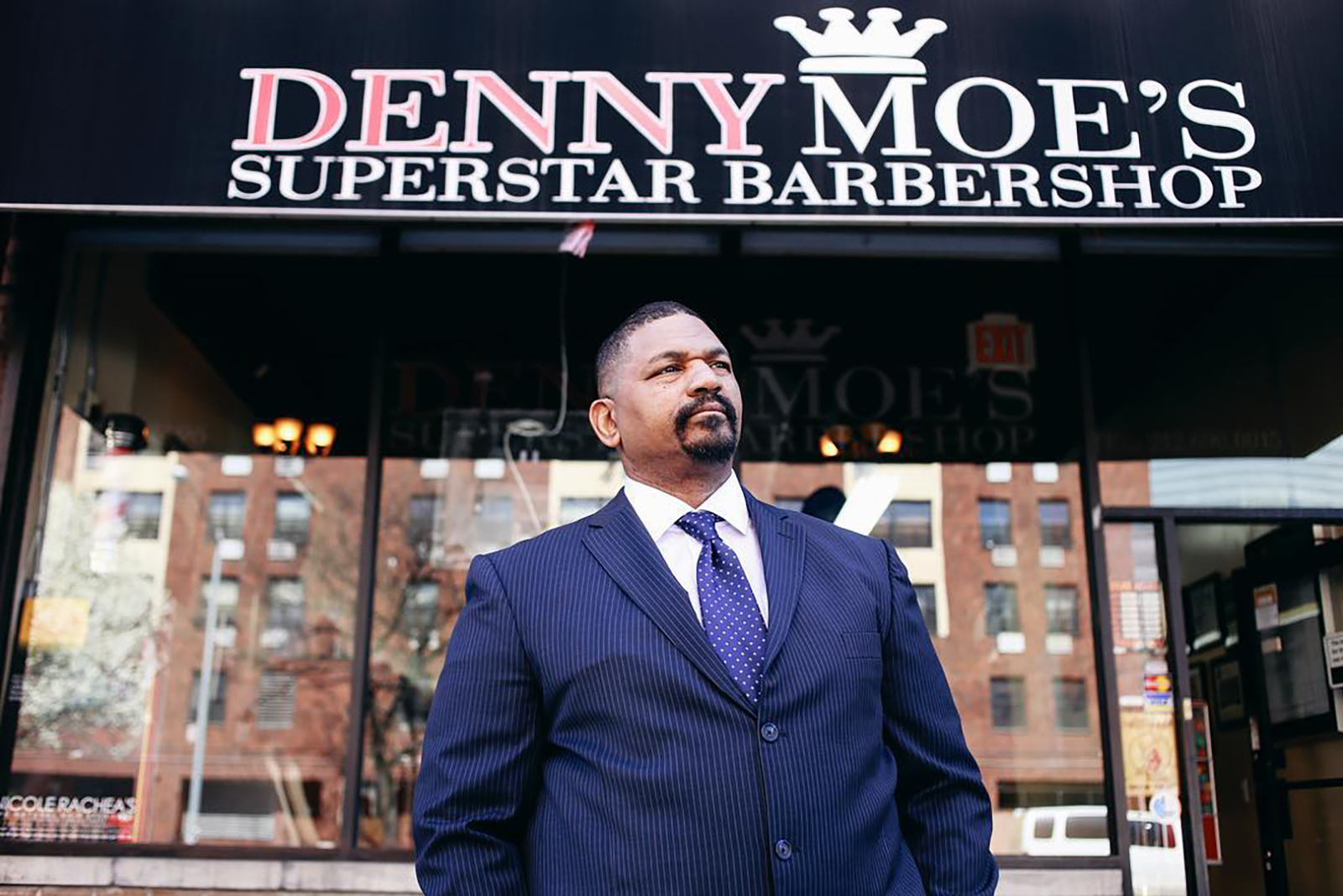 Dennis "Denny Moe" Mitchell, 54, stands outside of Denny Moe's Superstar Barbershop in Harlem, New York in an undated photo.