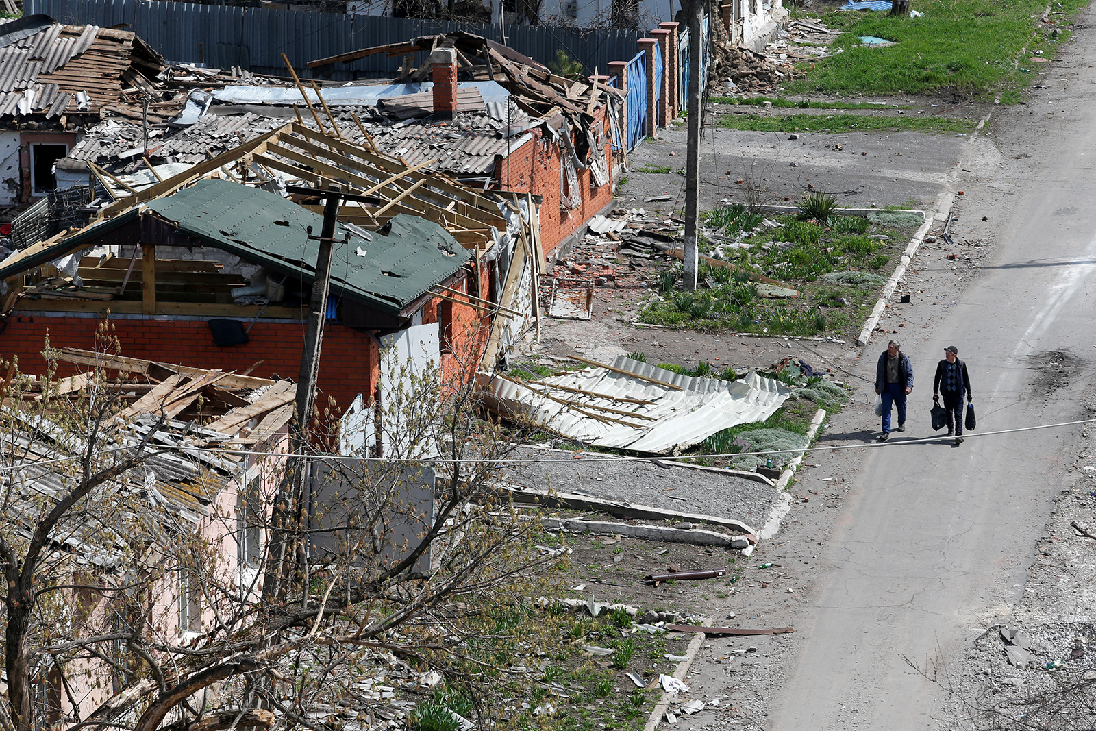 4月18日，乌克兰南部港口城市马里乌波尔，人们在受损建筑物附近行走。