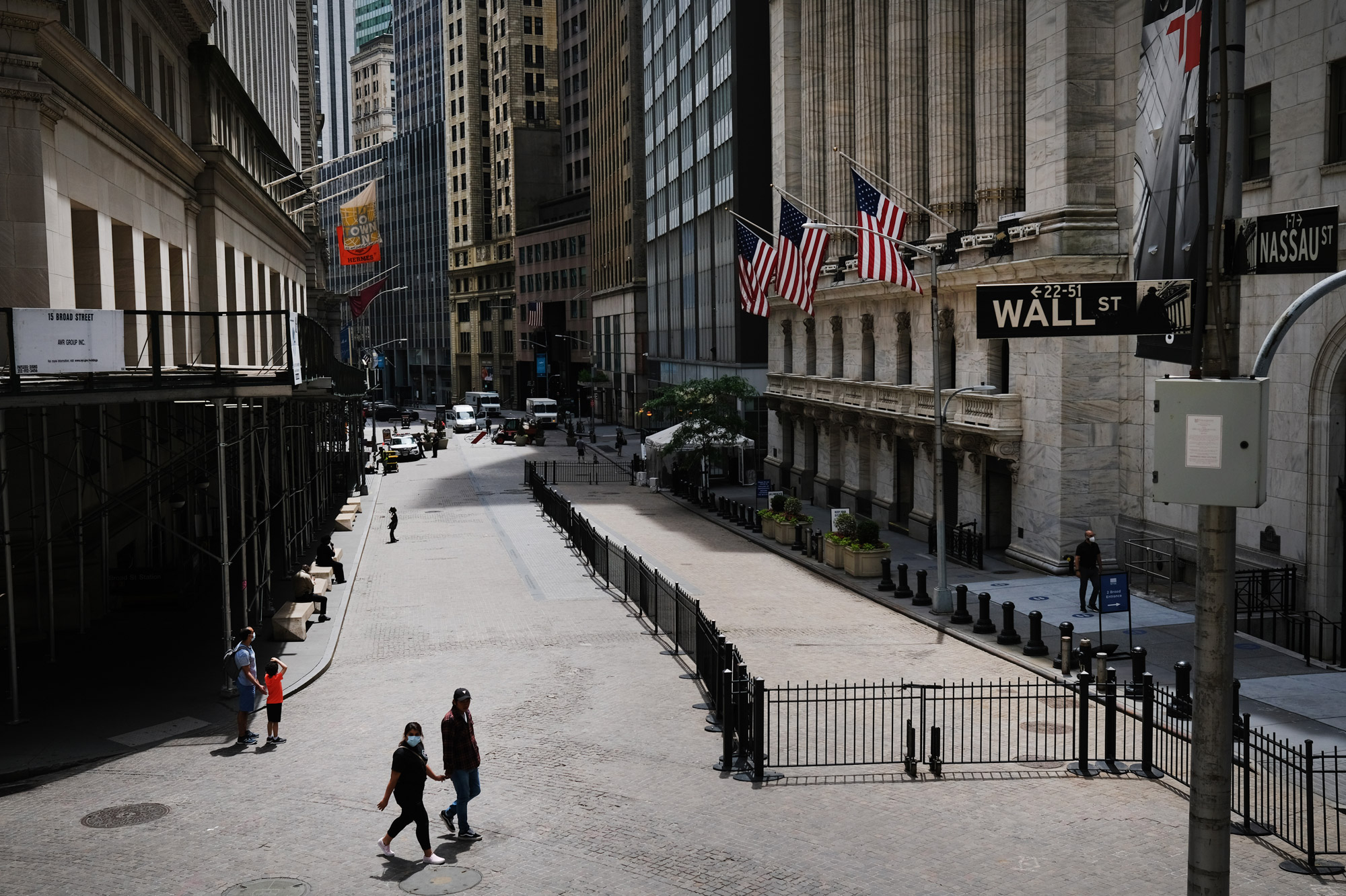 People walk by the New York Stock Exchange in an empty Financial District on June 15 in New York.