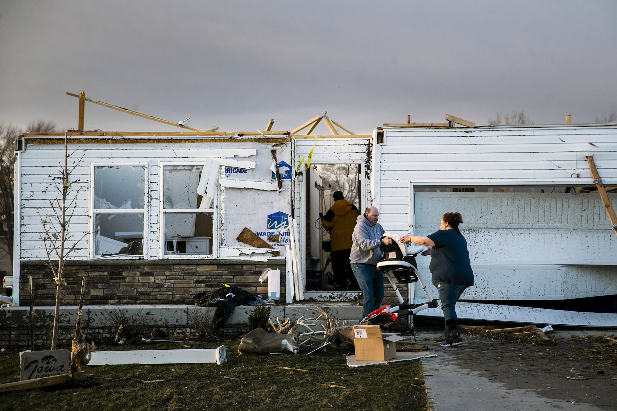 People help remove personal items from a storm damaged home after a tornado in Johnson County, Iowa, on Friday.