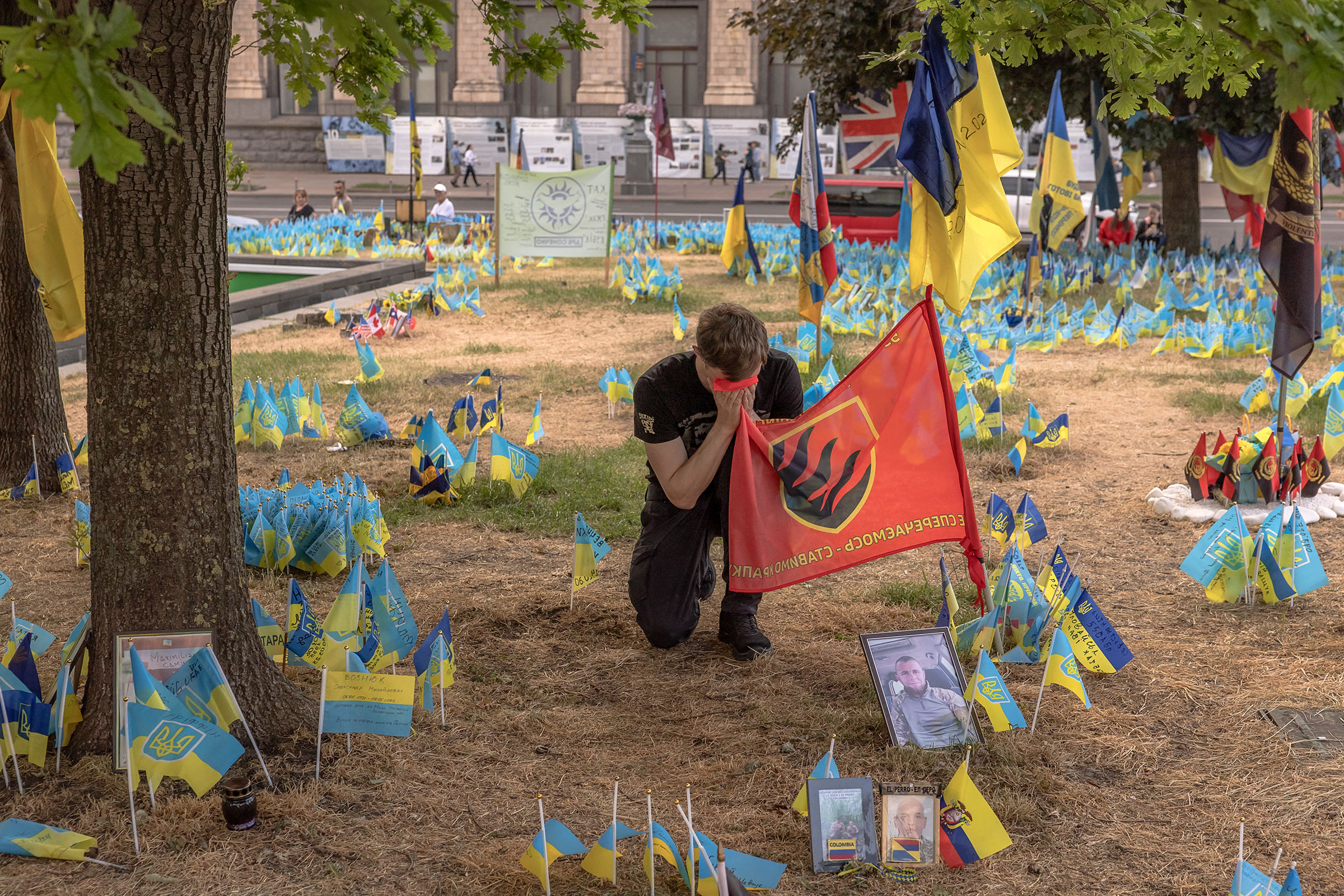 Ein Mann, der eine Flagge der ukrainischen 55. Artilleriebrigade hält, kniet am 27. Mai auf dem Unabhängigkeitsplatz in Kiew an einer Gedenkstätte mit ukrainischen und anderen Länderflaggen zum Gedenken an gefallene ukrainische und ausländische Kämpfer nieder.