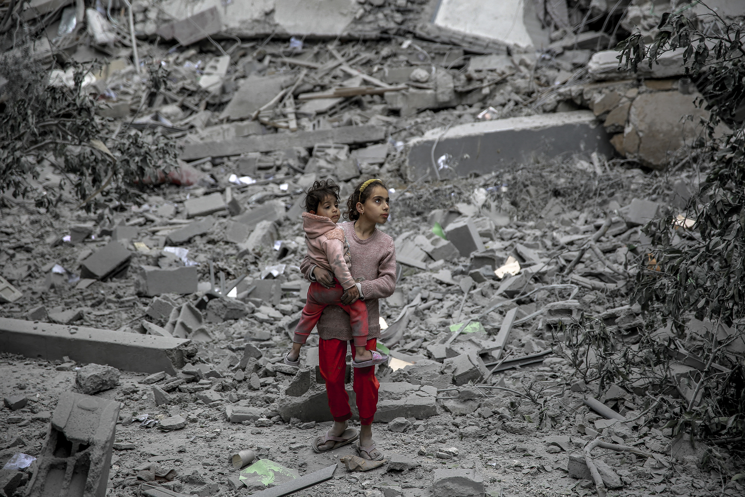 A Palestinian girl carries a child through the rubble of houses destroyed by Israeli bombardment in Gaza City on March 3.