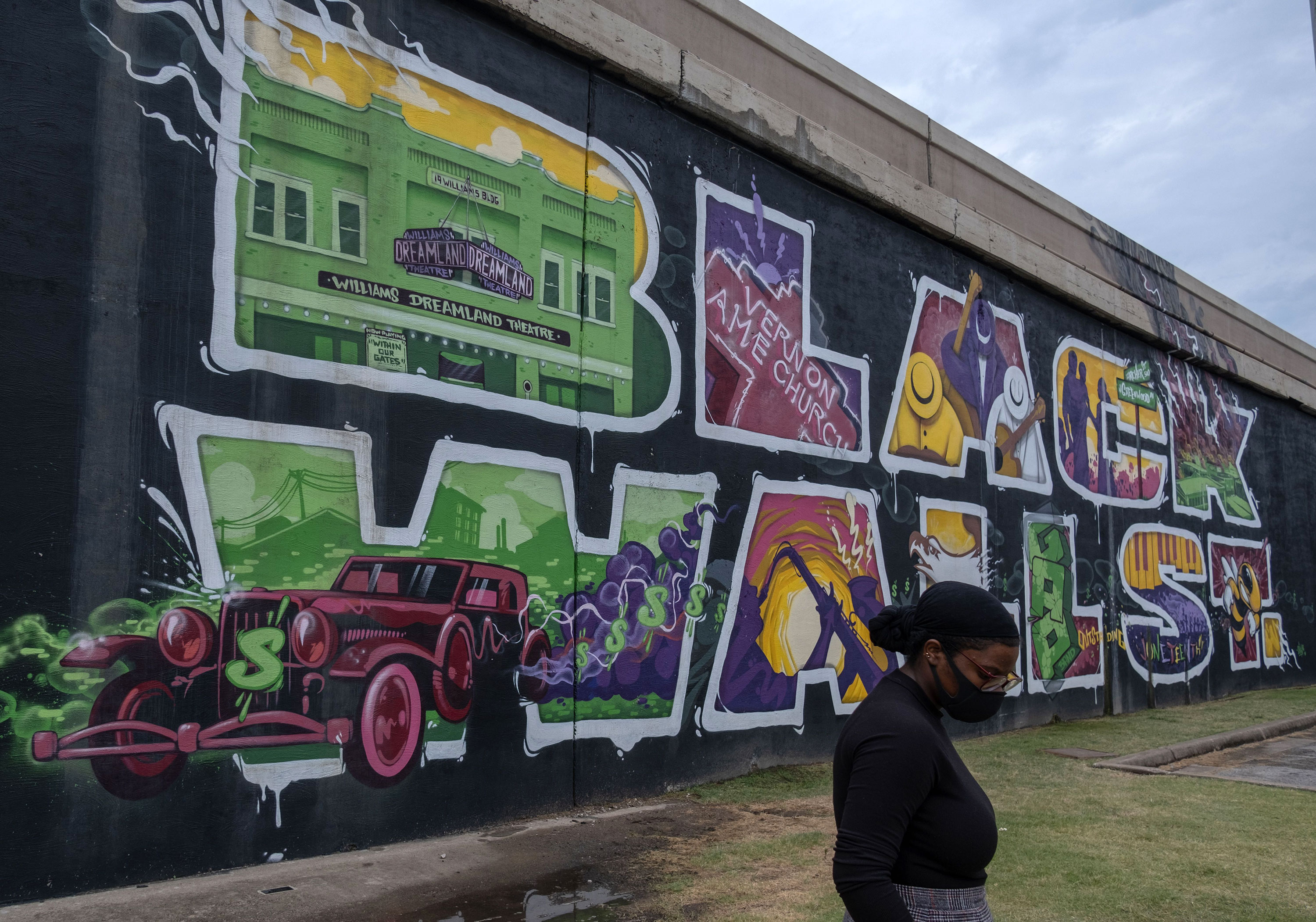 A woman walks past a mural in the Greenwood district of Tulsa, Oklahoma, in June 2020.