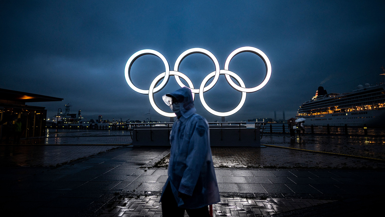 A man walks past the Olympic Rings lit up at dusk in Yokohama on July 2.