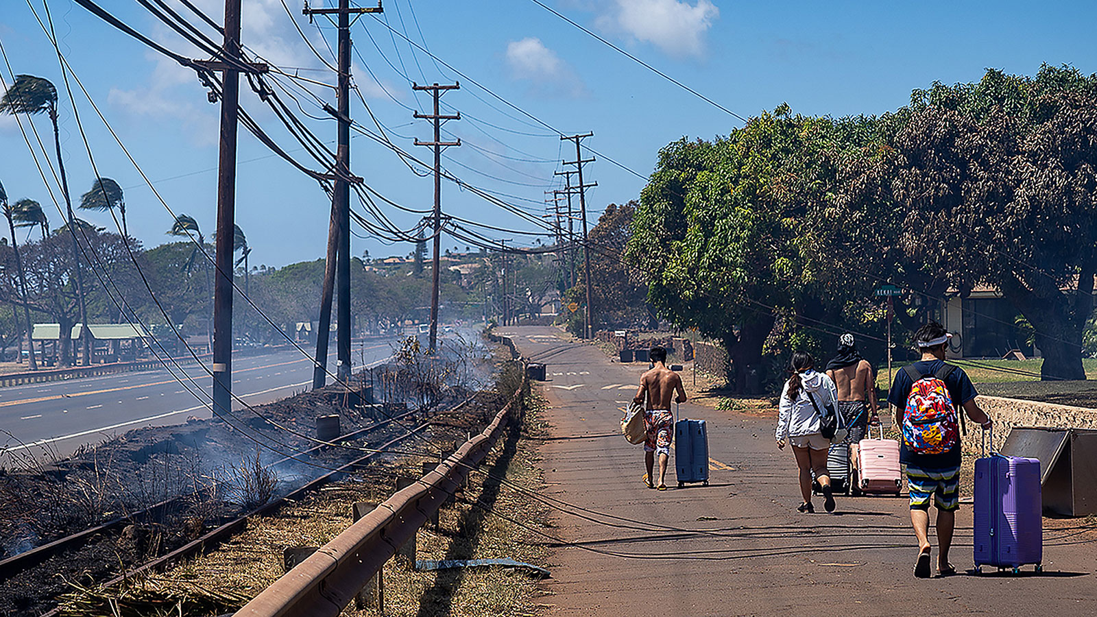 Residents carry their belongings in suitcases on Thursday, August 10, after wildfires swept through Lahaina on Wednesday. 