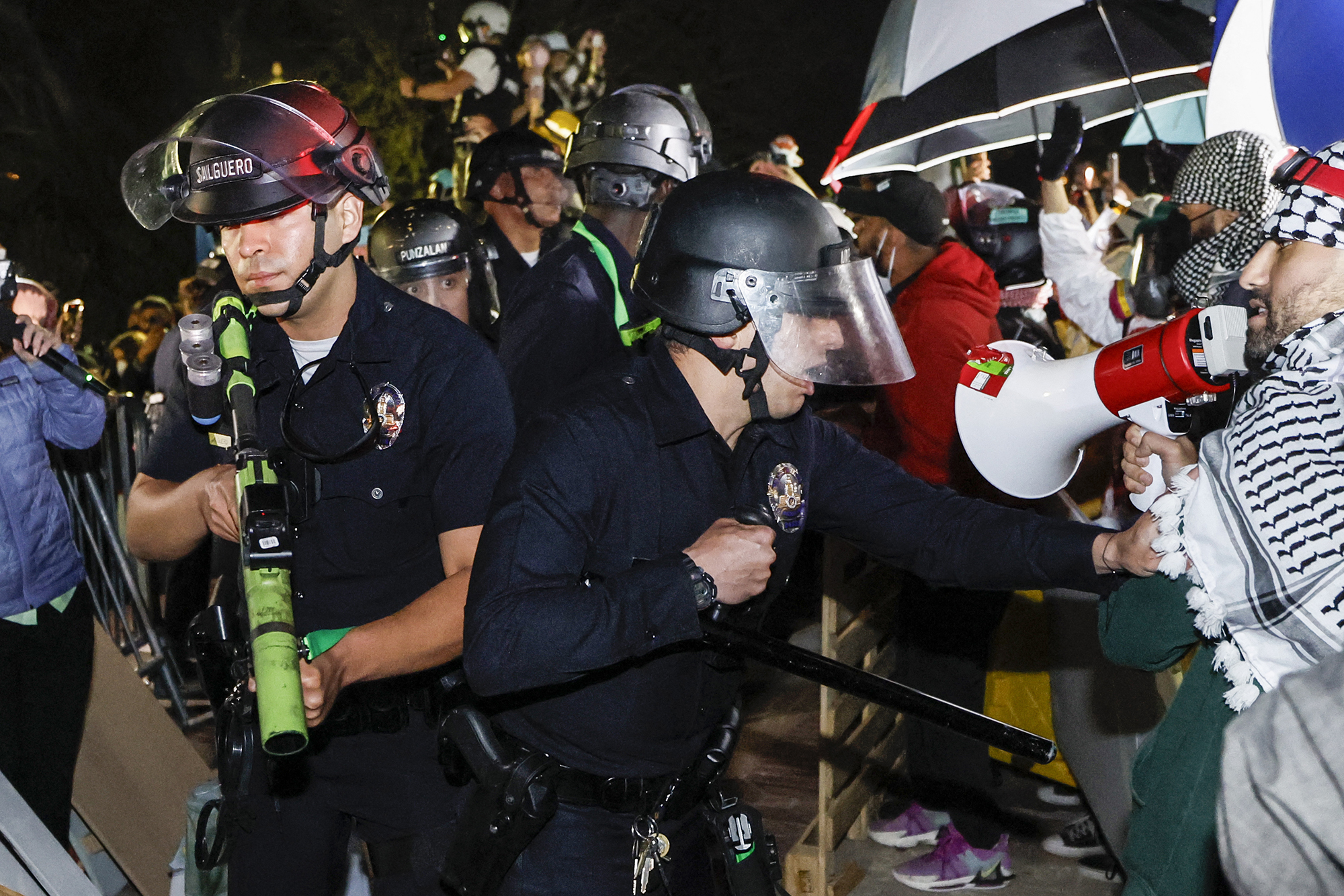 Police react while pro-Palestinian students stand their ground after police breached their encampment at the campus of the University of California, Los Angeles, California, early on May 2.
