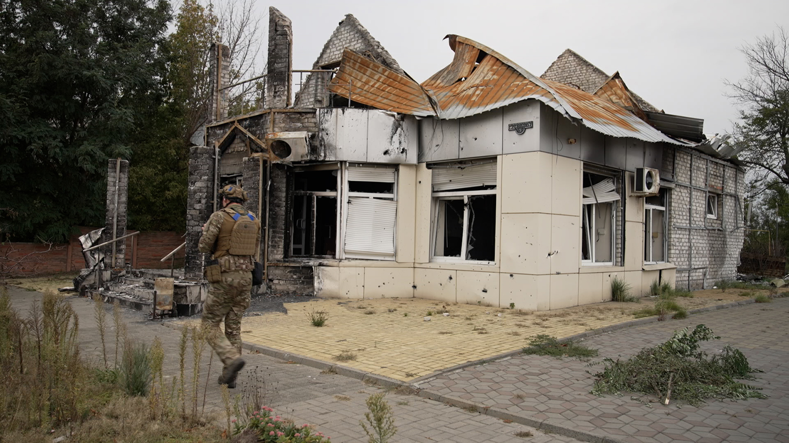 A Ukrainian soldier with the Dnipro 1 brigade walks past a damaged building in central Lyman, Ukraine, on Sunday, October 3, 2022.