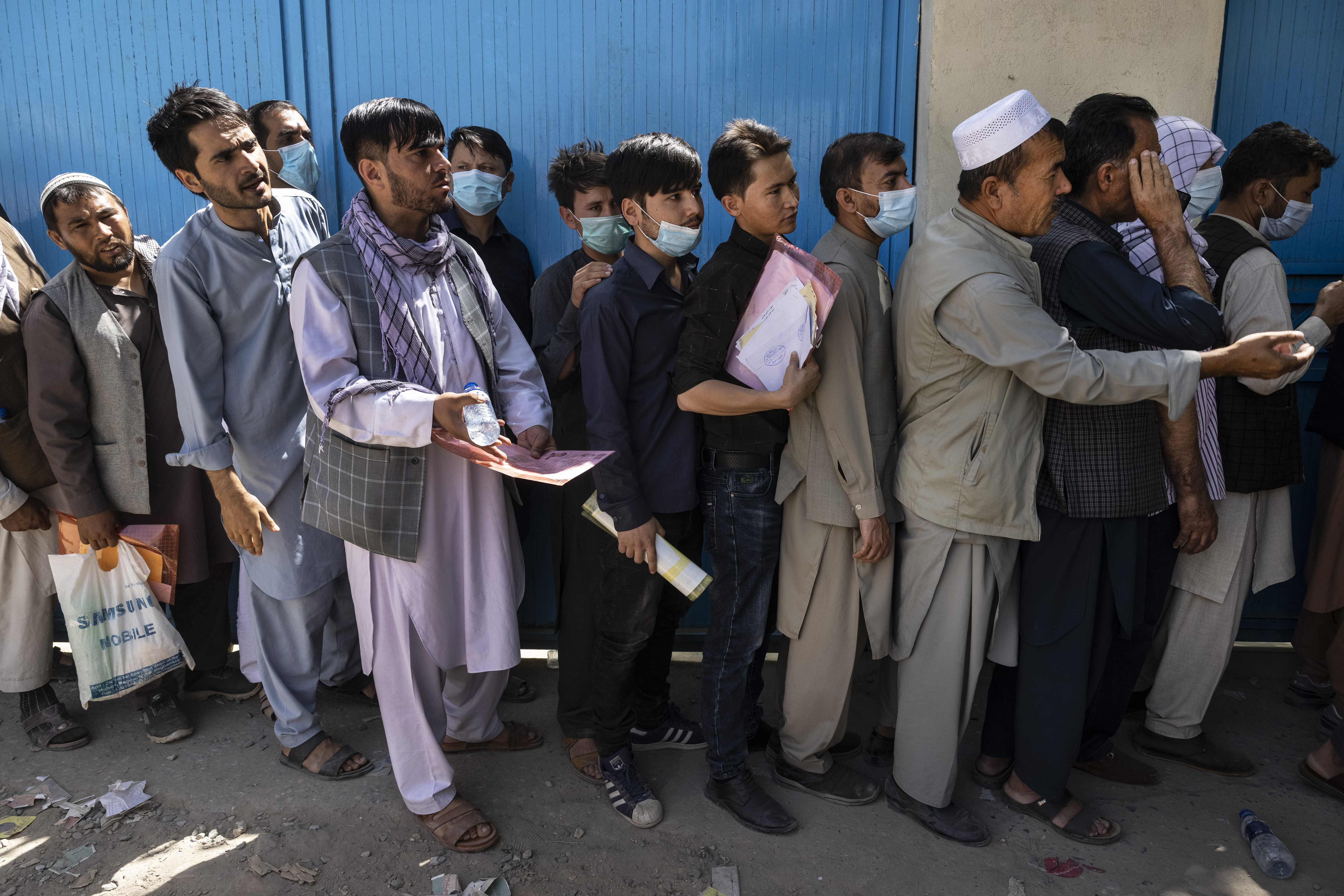 Afghans wait in long lines for hours at the passport office as many are desperate to have their travel documents ready to go in Kabul, Afghanistan on Saturday. 