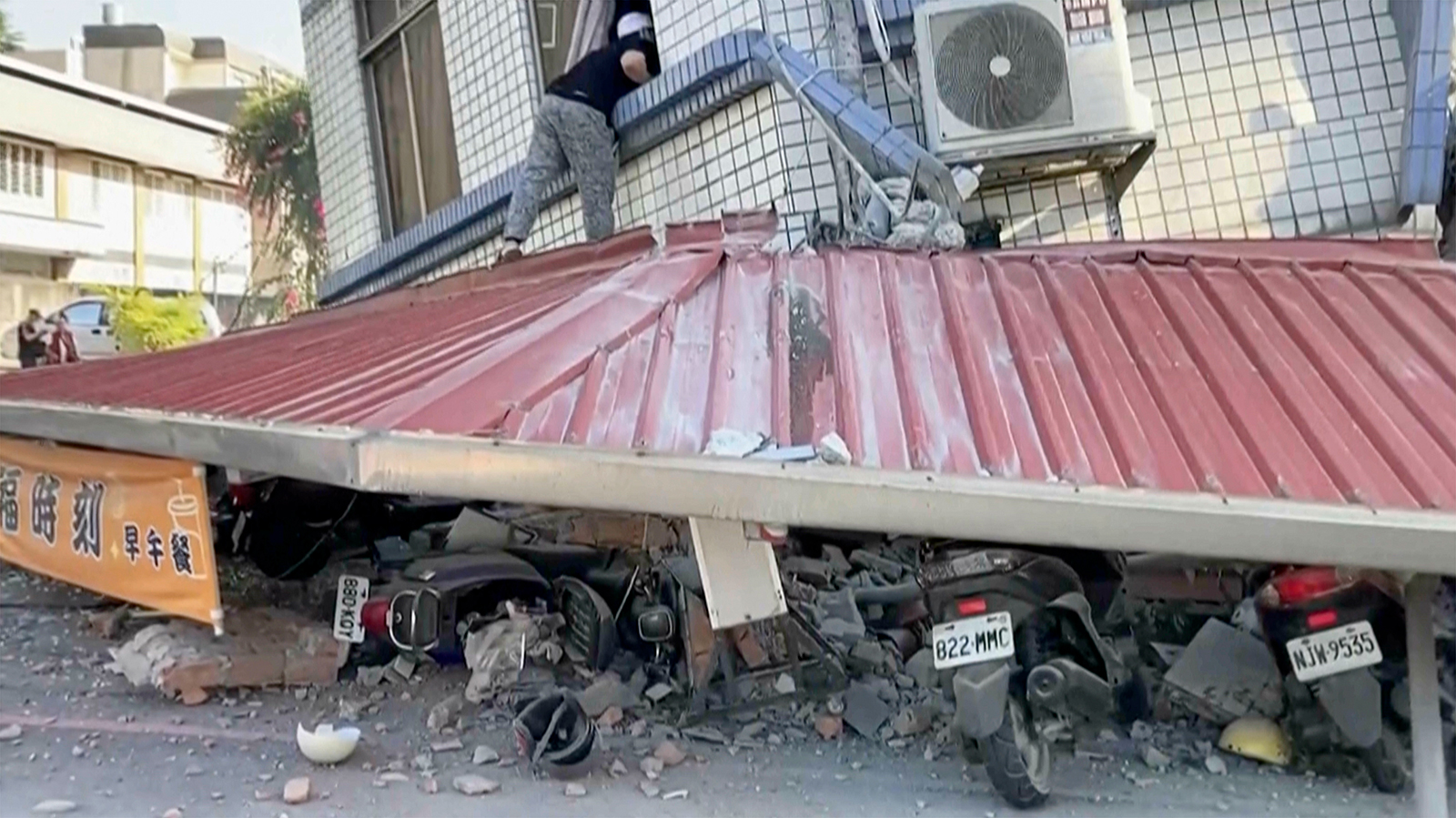 In this image taken from a video footage run by TVBS, a man checks a partially collapsed building in Hualien, eastern Taiwan on Wednesday, April 3.