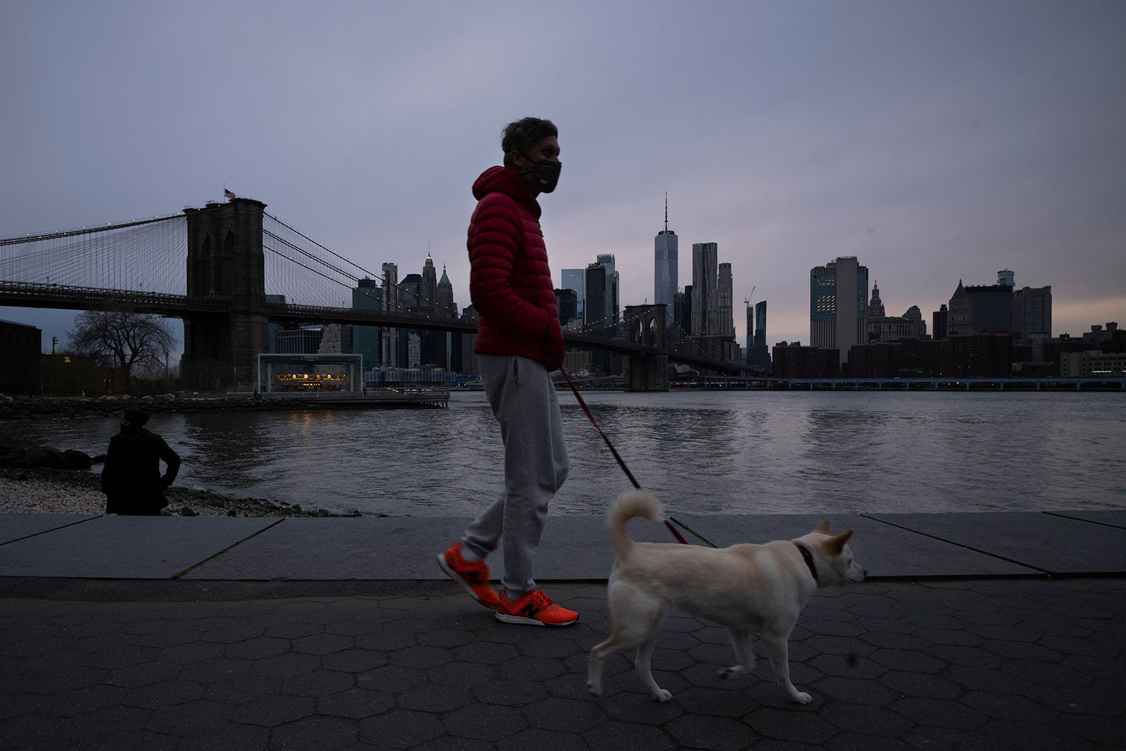 A man wears a mask while walking his dog in Brooklyn Bridge Park on Tuesday, April 14.