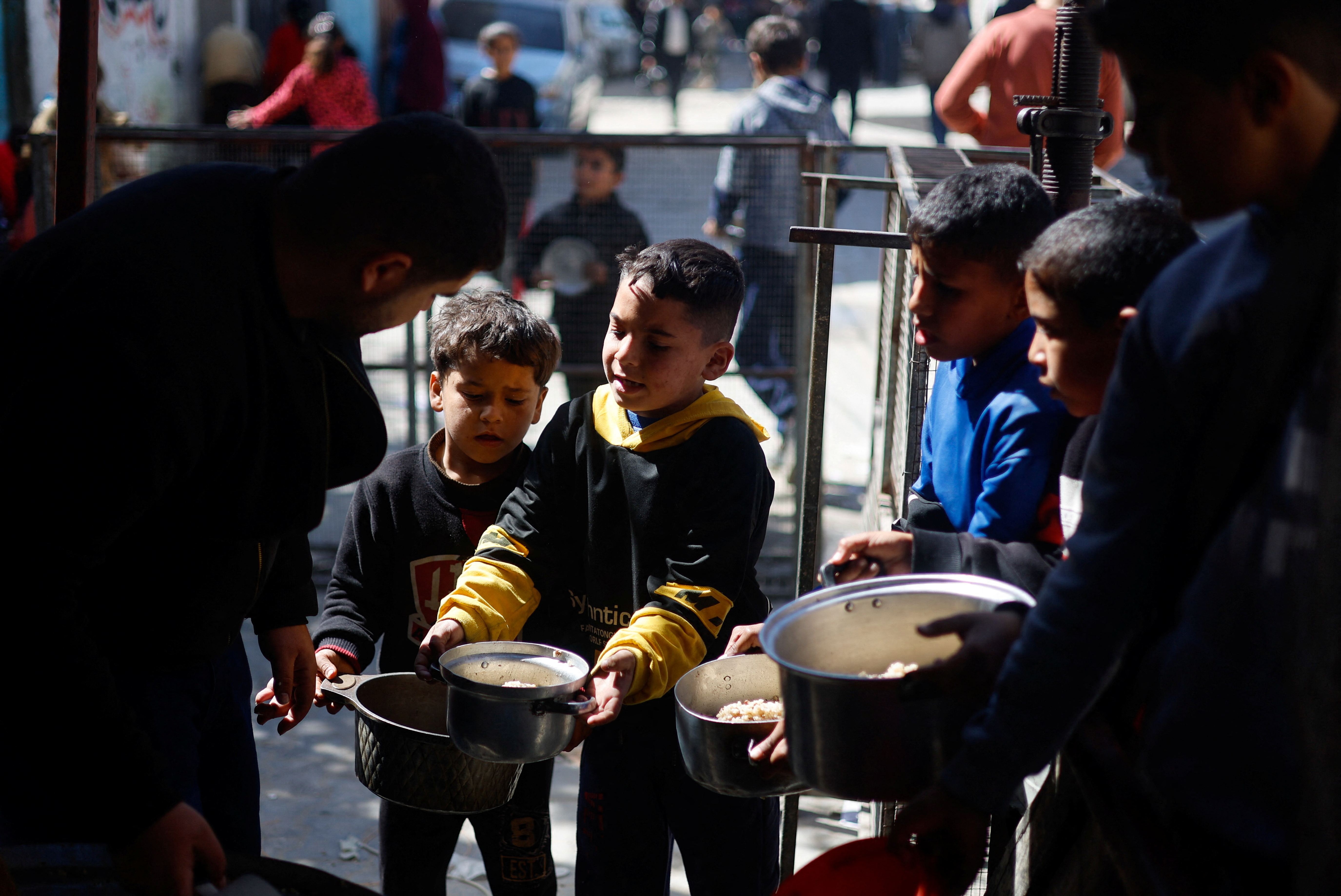 Children wait to receive food cooked by a charity kitchen amid shortages of food supplies in Rafah, Gaza, on March 5.