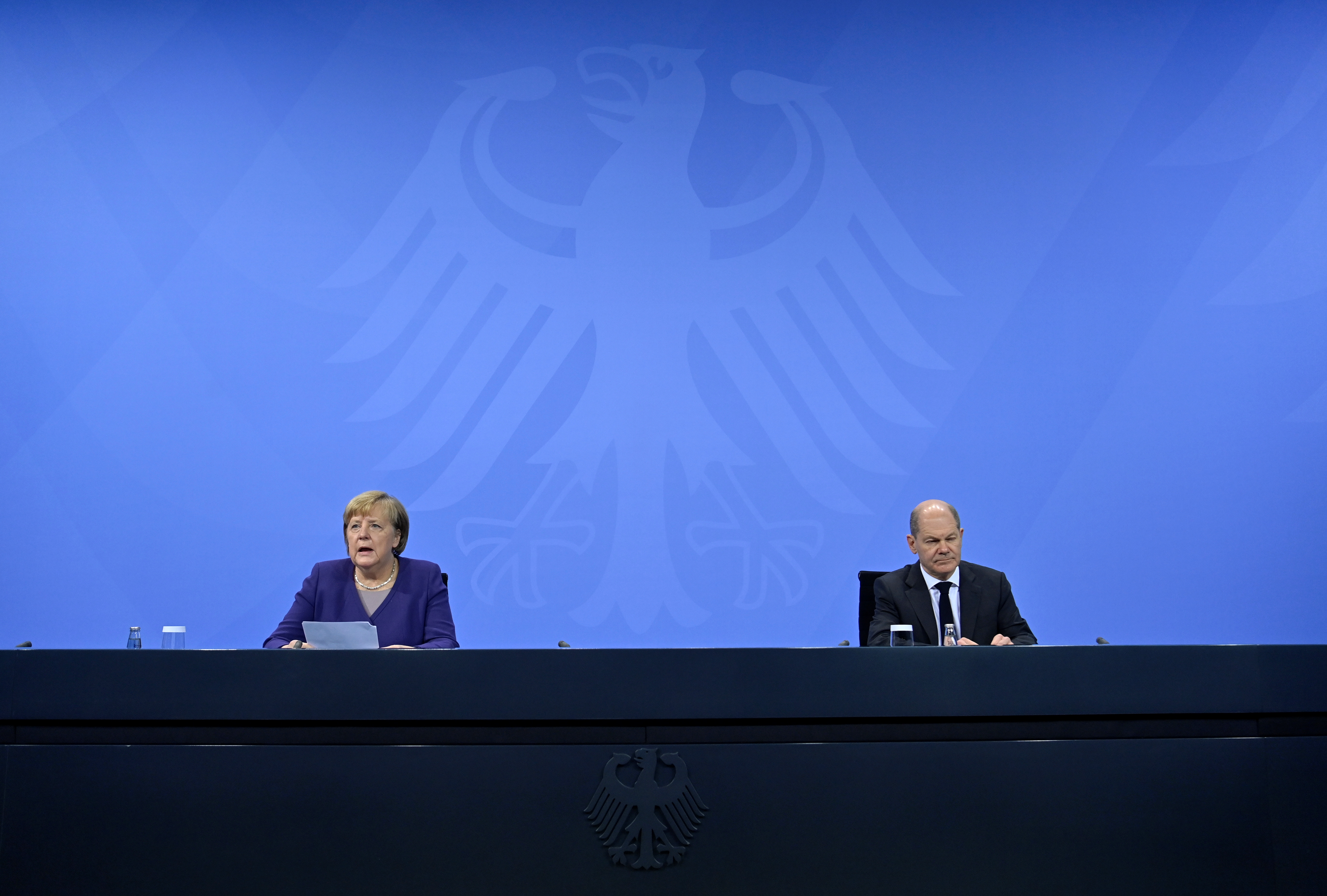 German Chancellor Angela Merkel (L) and her designated successor Olaf Scholz (R) address a press conference following a meeting with the heads of government of Germany's federal states at the Chancellery in Berlin, Germany December 2, 2021. 