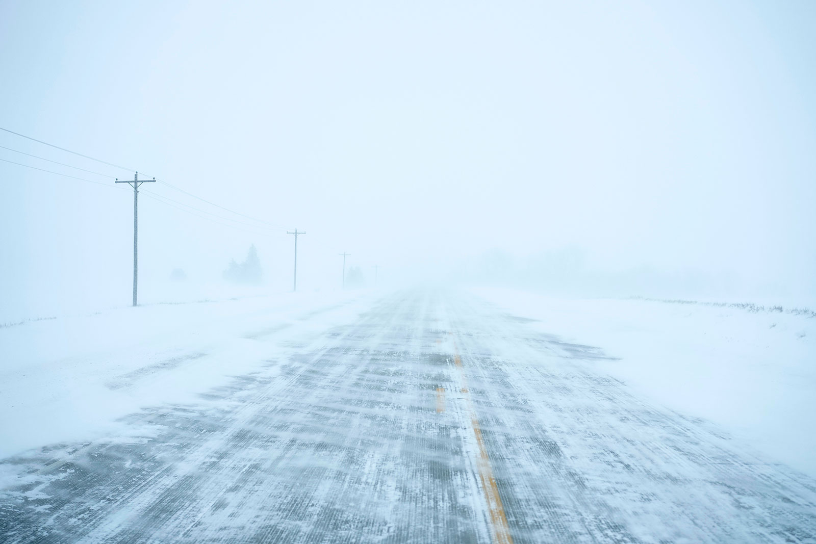 Snow blows over a county road near Merrill, Iowa, on Friday