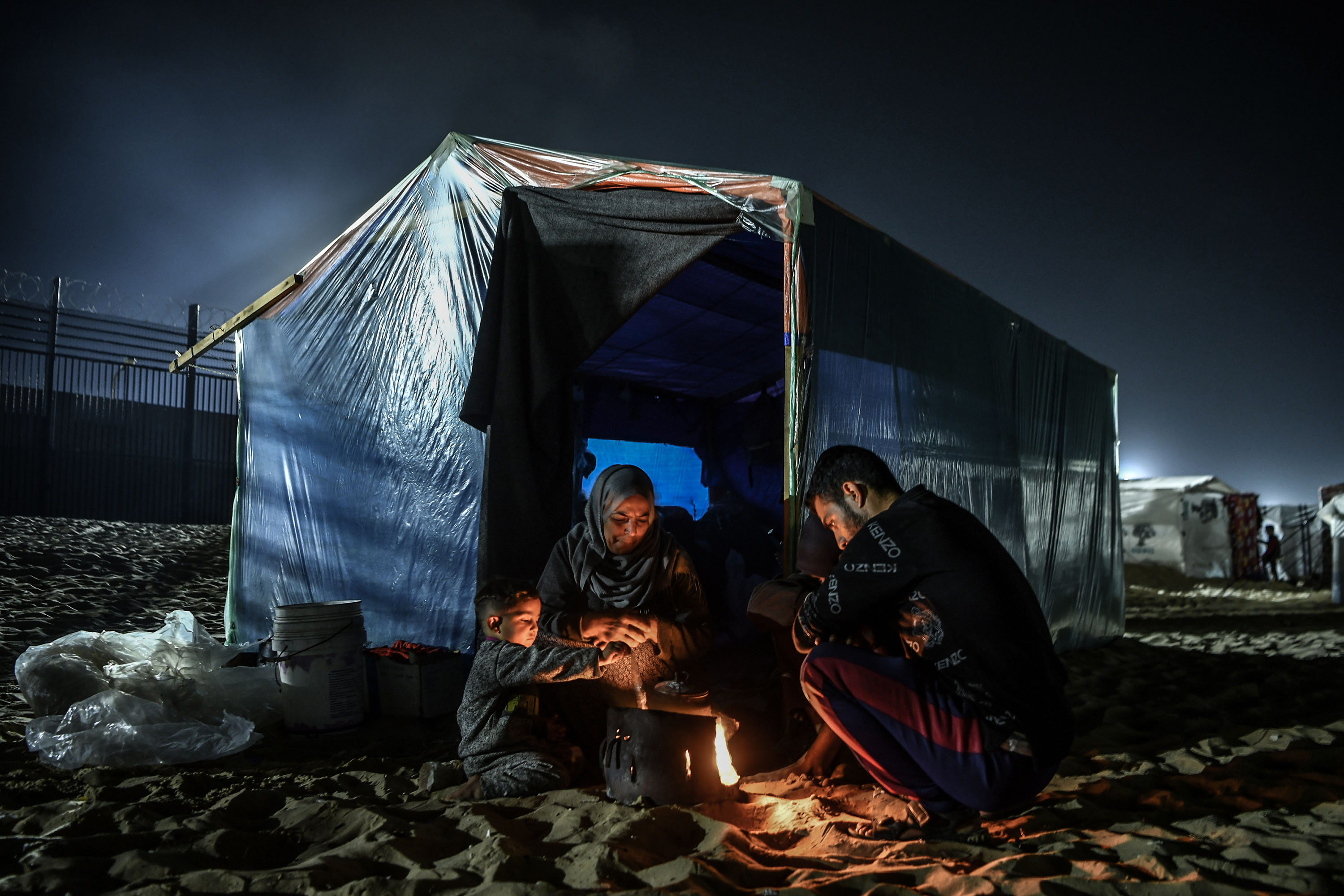 Members of a Palestinian family warm themselves beside a campfire and makeshift tent, near the Egyptian border in Rafah, Gaza, on February 27.