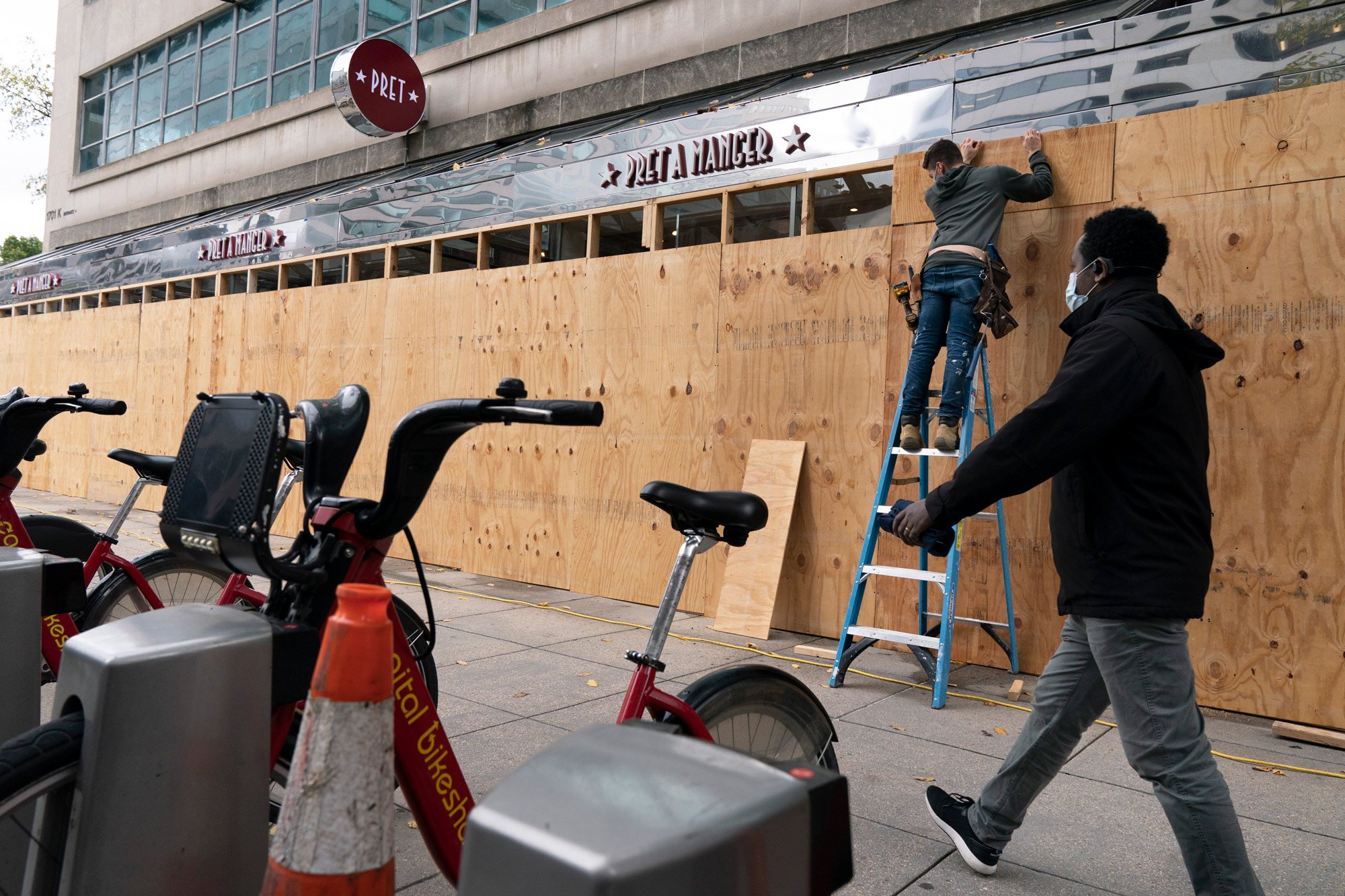 A pedestrian passes work being done to board up a Pret A Manger restaurant along K Street on October 30.