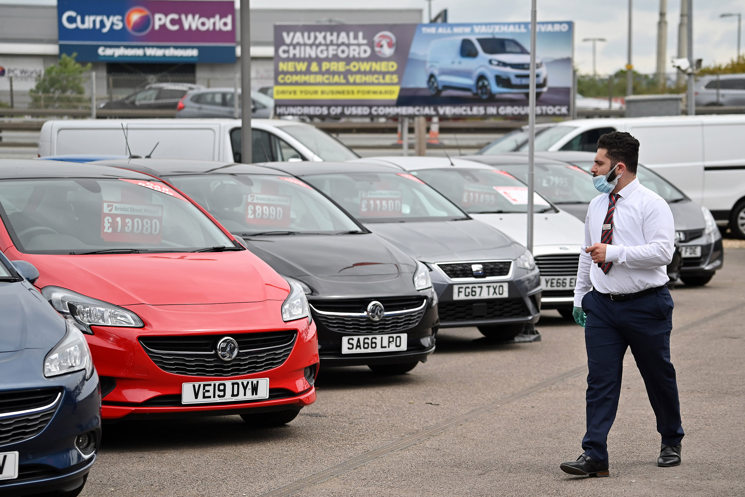 A car salesperson wearing PPE (personal protective equipment) walks past vehicles parked at the  Vauxhall car dealership on June 4, in London, England. 