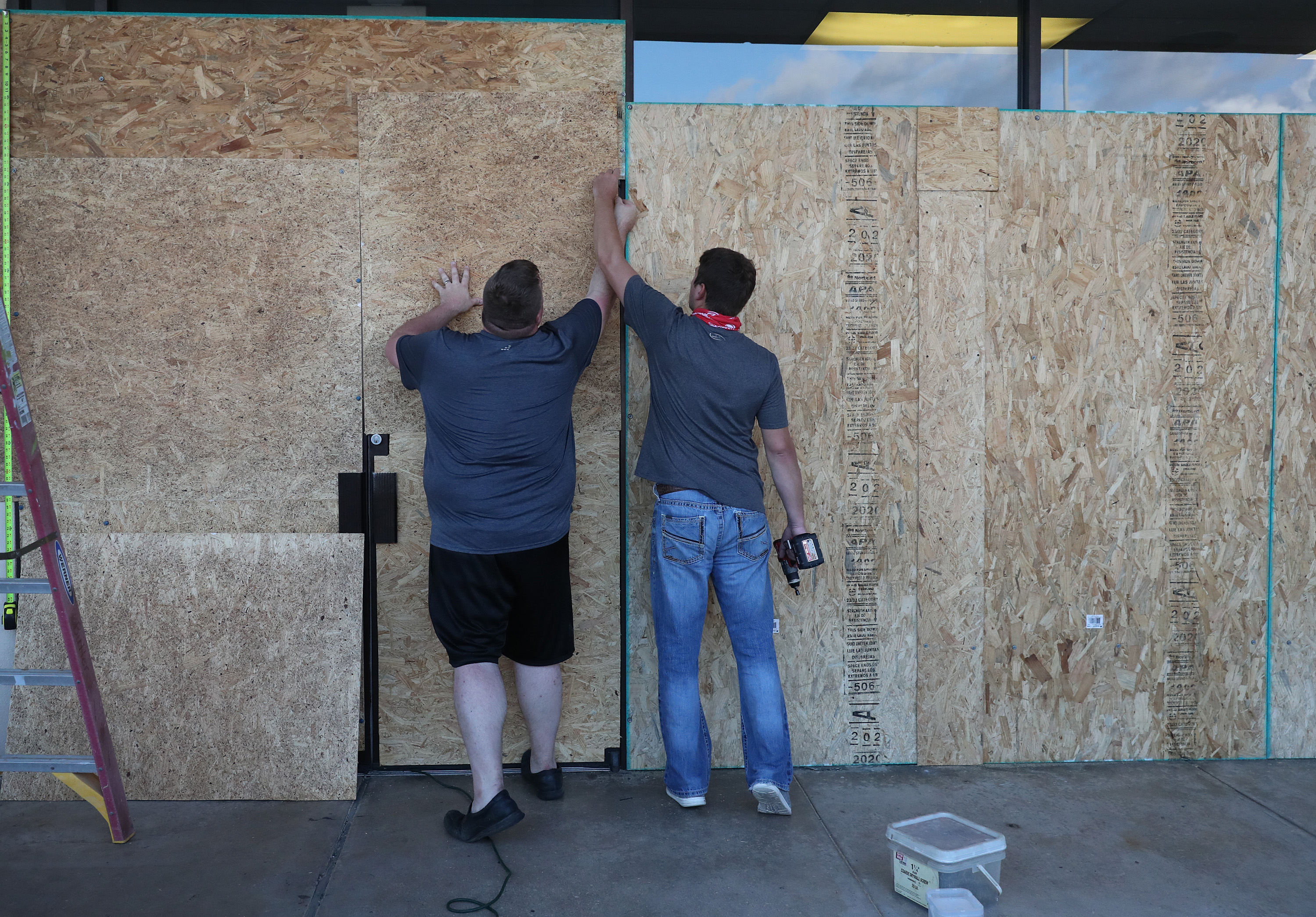 Tyler Arnold and David Lohr work on placing plywood over the windows of a business before the arrival of Hurricane Laura on Tuesday in Lake Charles, Louisiana.