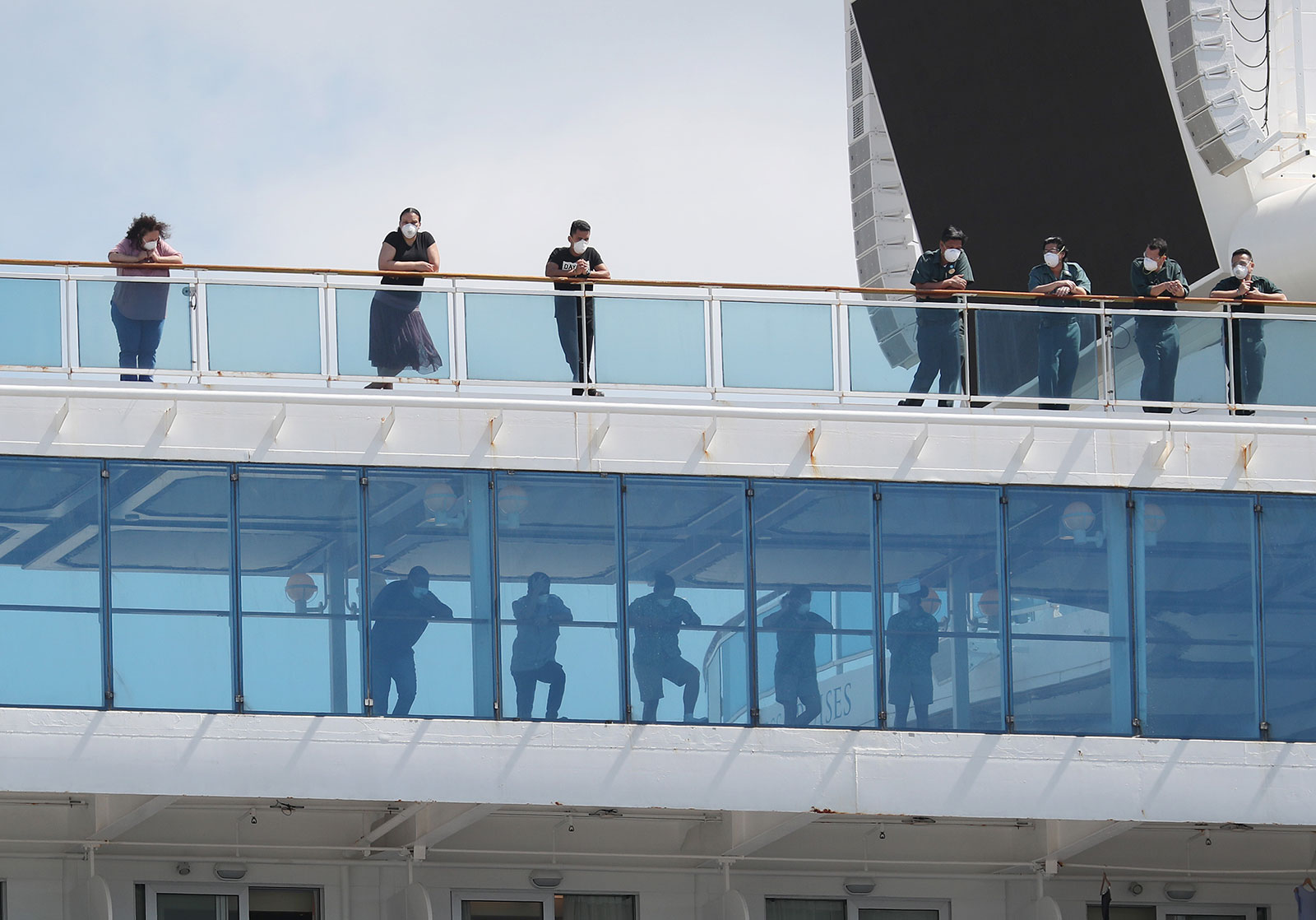 Passengers look out from the deck of the Coral Princess cruise ship in Miami, Florida, on April 4.