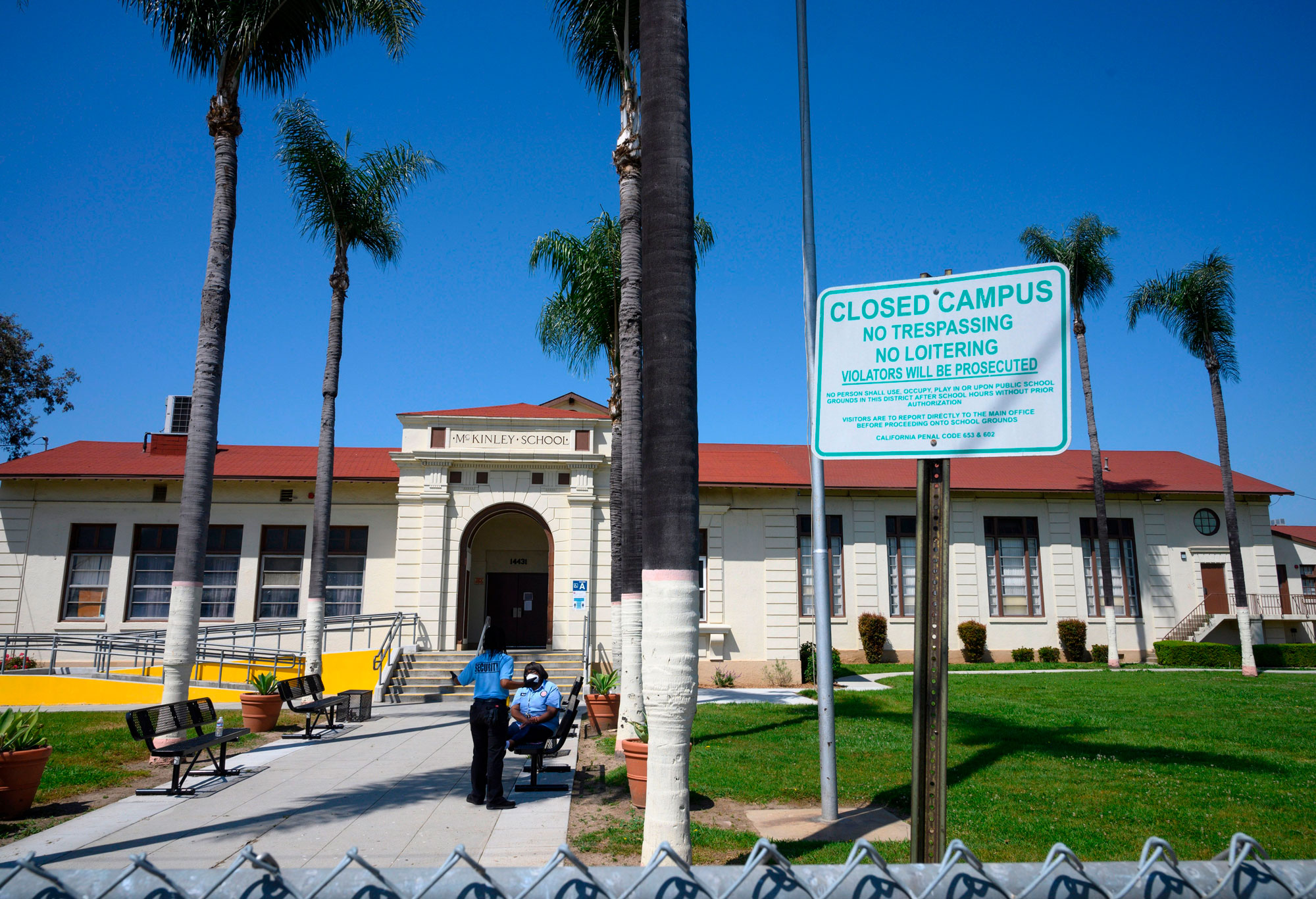 Two security guards talk on the campus of the closed McKinley School, part of the Los Angeles Unified School District system, in Compton, California, on April 28.
