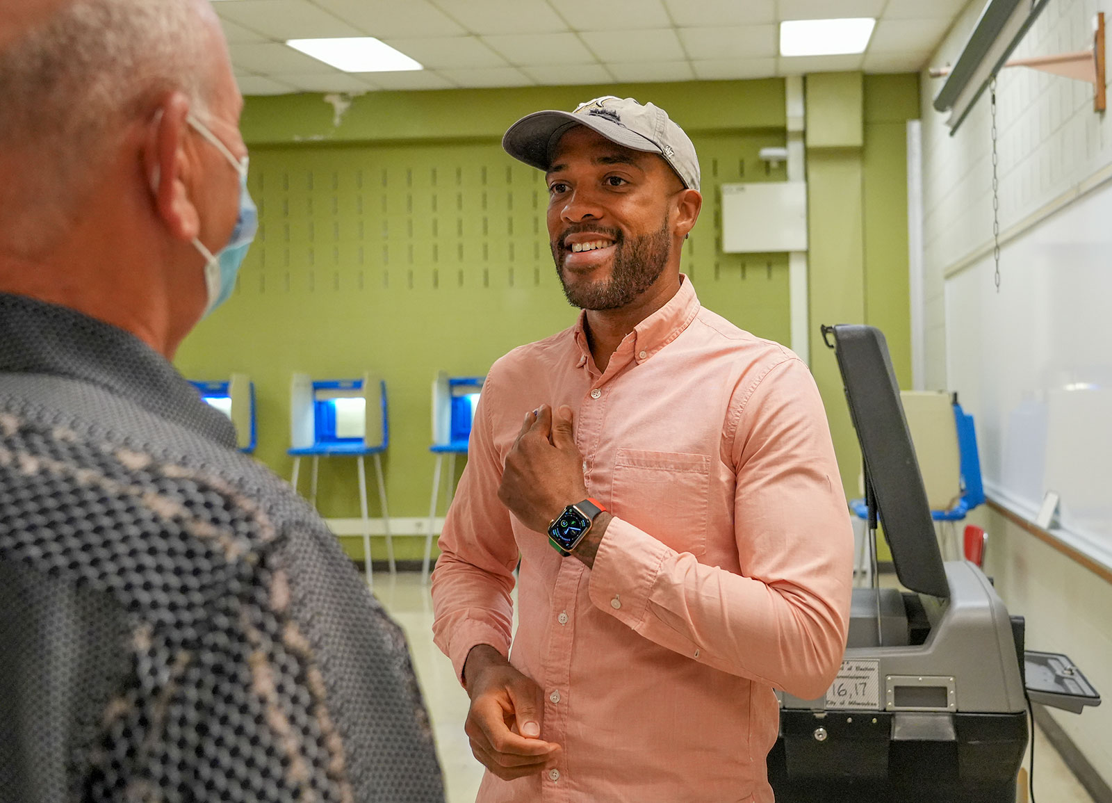 Mandela Barnes speaks with Gary Sprong as he places an "I Voted" sticker on his chest on August 9. 