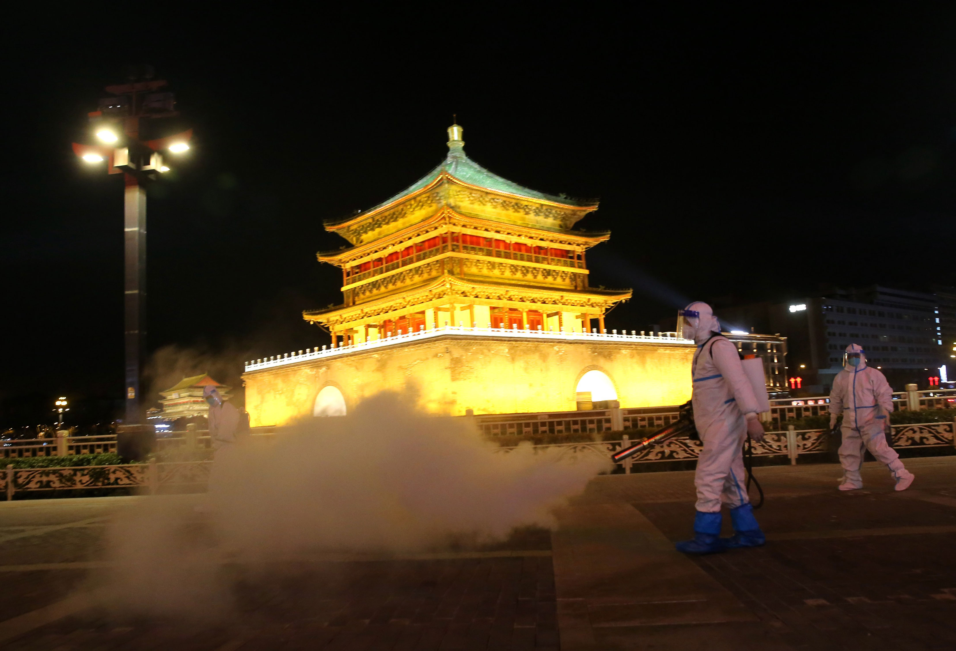 Staff members in protective suits disinfect around Xi'an Bell Tower on December 26, 2021 in Xi'an, Shaanxi Province, China.