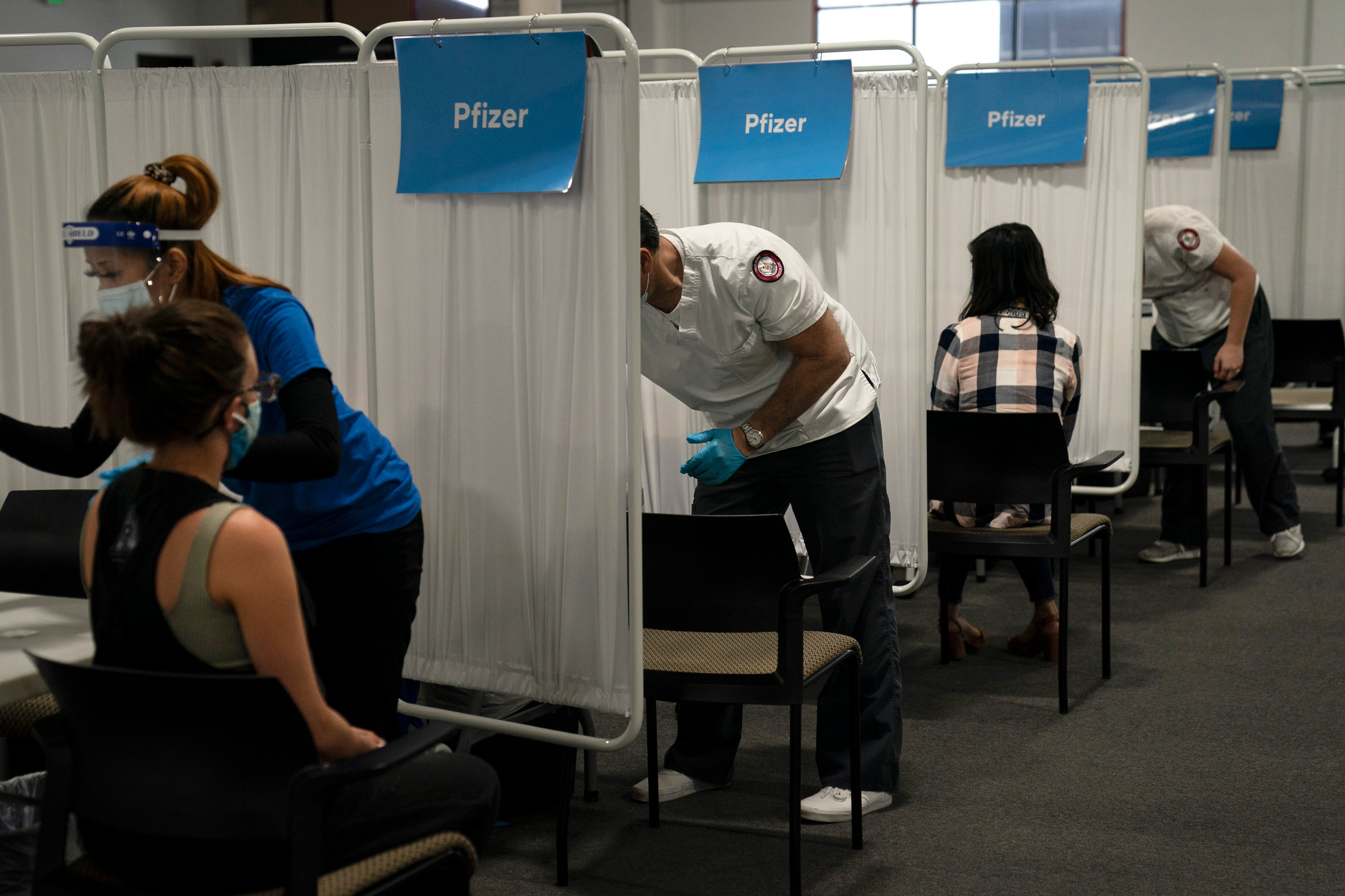 Student nurse Dario Gomez, center, disinfects a chair after administering the Pfizer COVID-19 vaccine to a patient at Providence Edwards Lifesciences vaccination site in Santa Ana, California, on May 21.