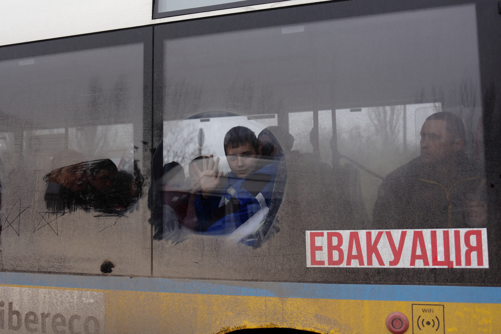 A boy waves as he leaves on an evacuation bus in Kherson on Thursday.