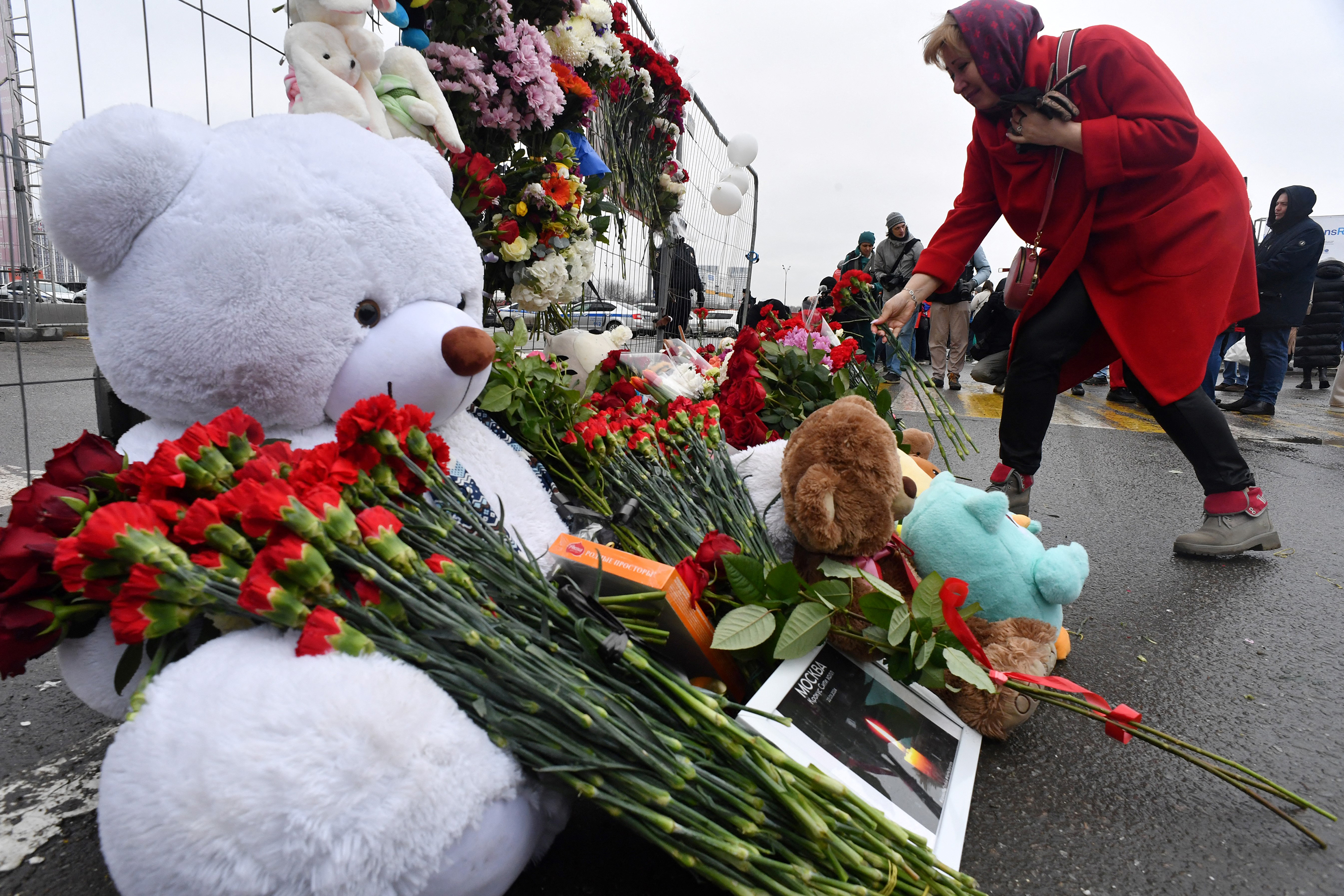 A woman lays flowers at a makeshift memorial in front of the Crocus City Hall in Moscow, on Saturday, March 23. 