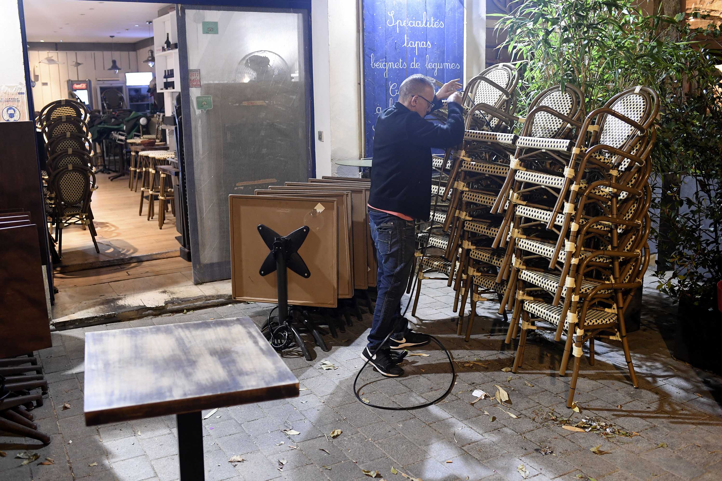 A restaurant owner removes chairs and tables on a terrace in Marseille on September 27, as the city closes for seven days due to the coronavirus outbreak.