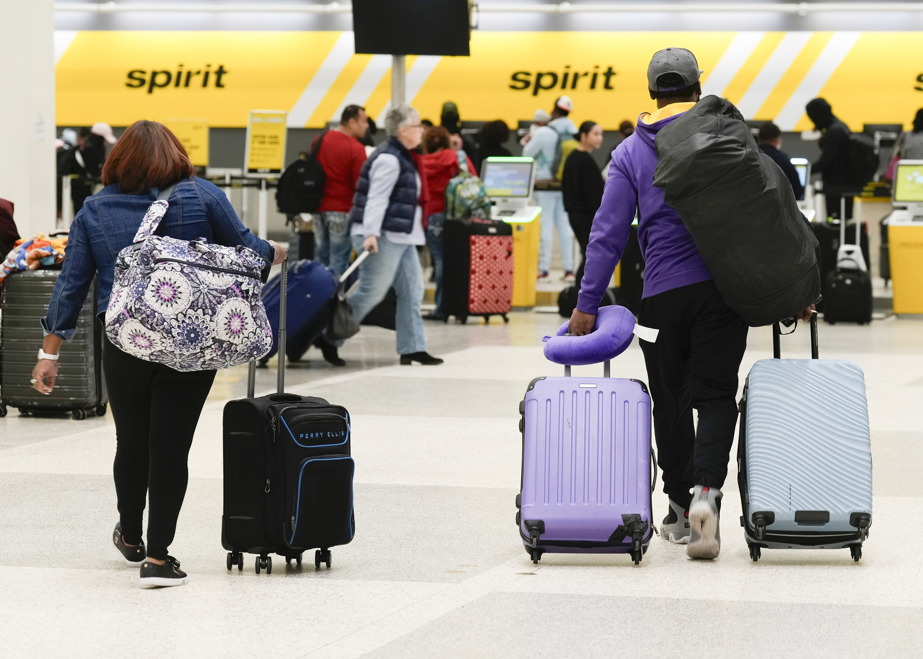 Travelers wheel luggage toward Spirit Airlines check-in desk at George Bush Intercontinental Airport, on November 21, in Houston.