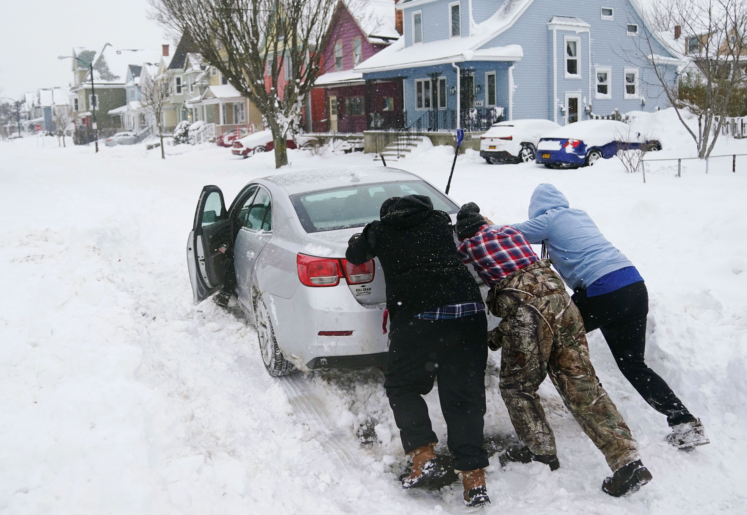 Neighbors help push a motorist stuck in the snow in Buffalo on Monday.