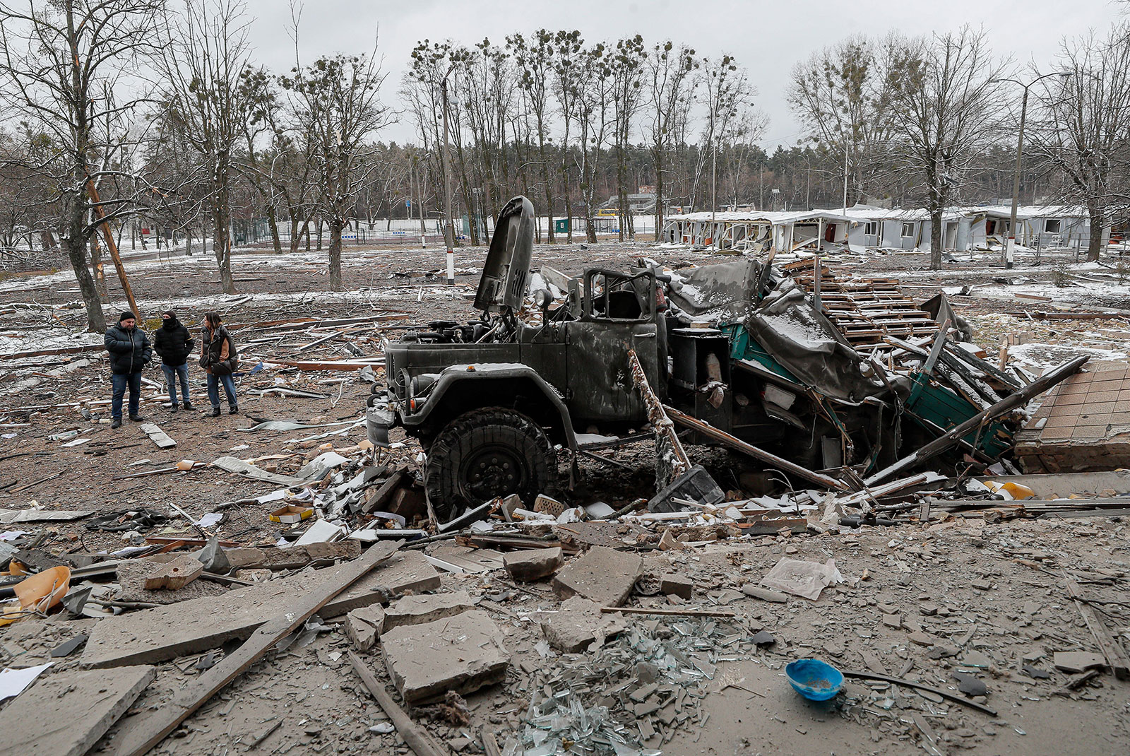 People stand next to a damaged military vehicle after a shelling near Kyiv on March 1.