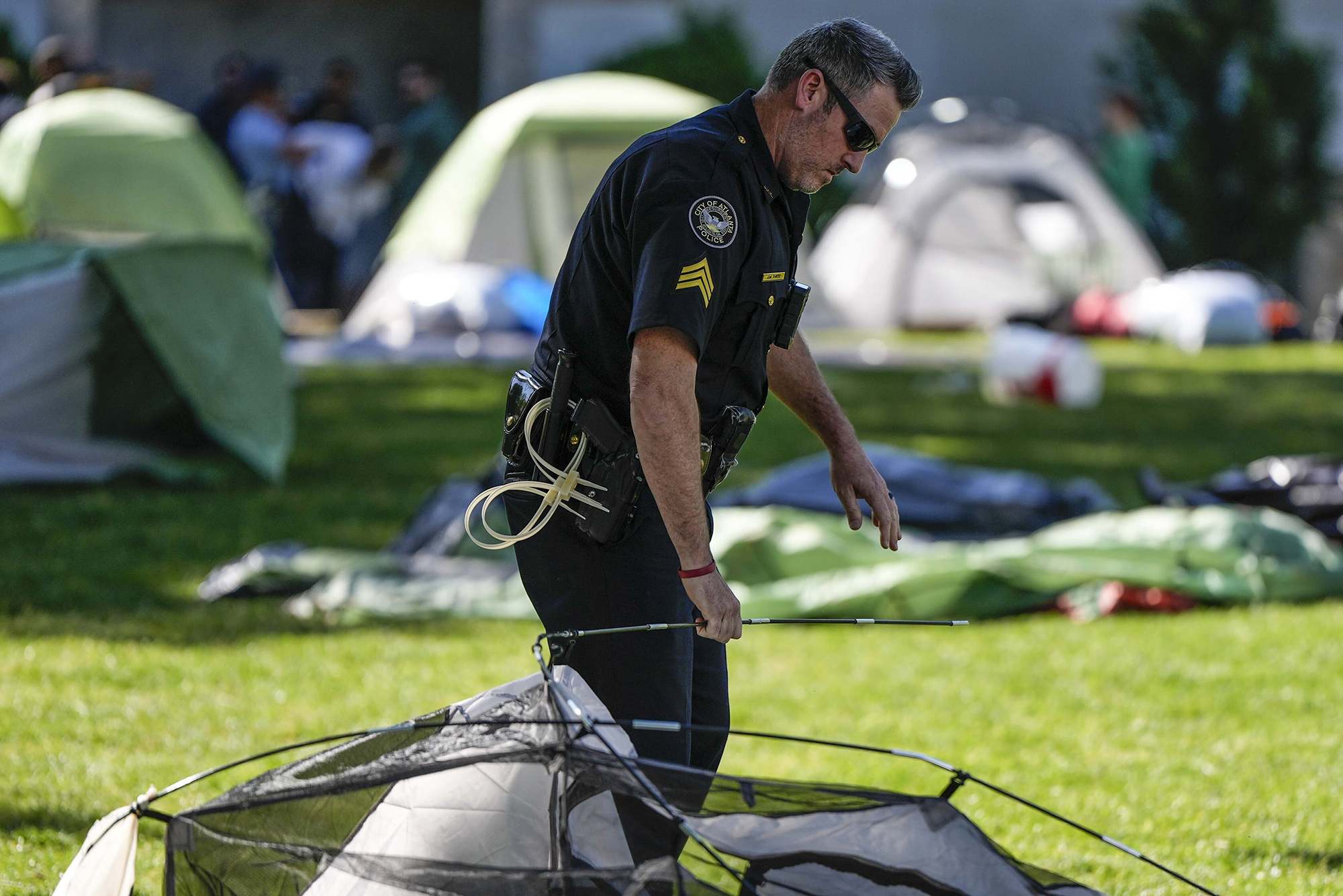 An Atlanta police officer takes down tents on the campus of Emory University after a pro-Palestinian demonstration today.