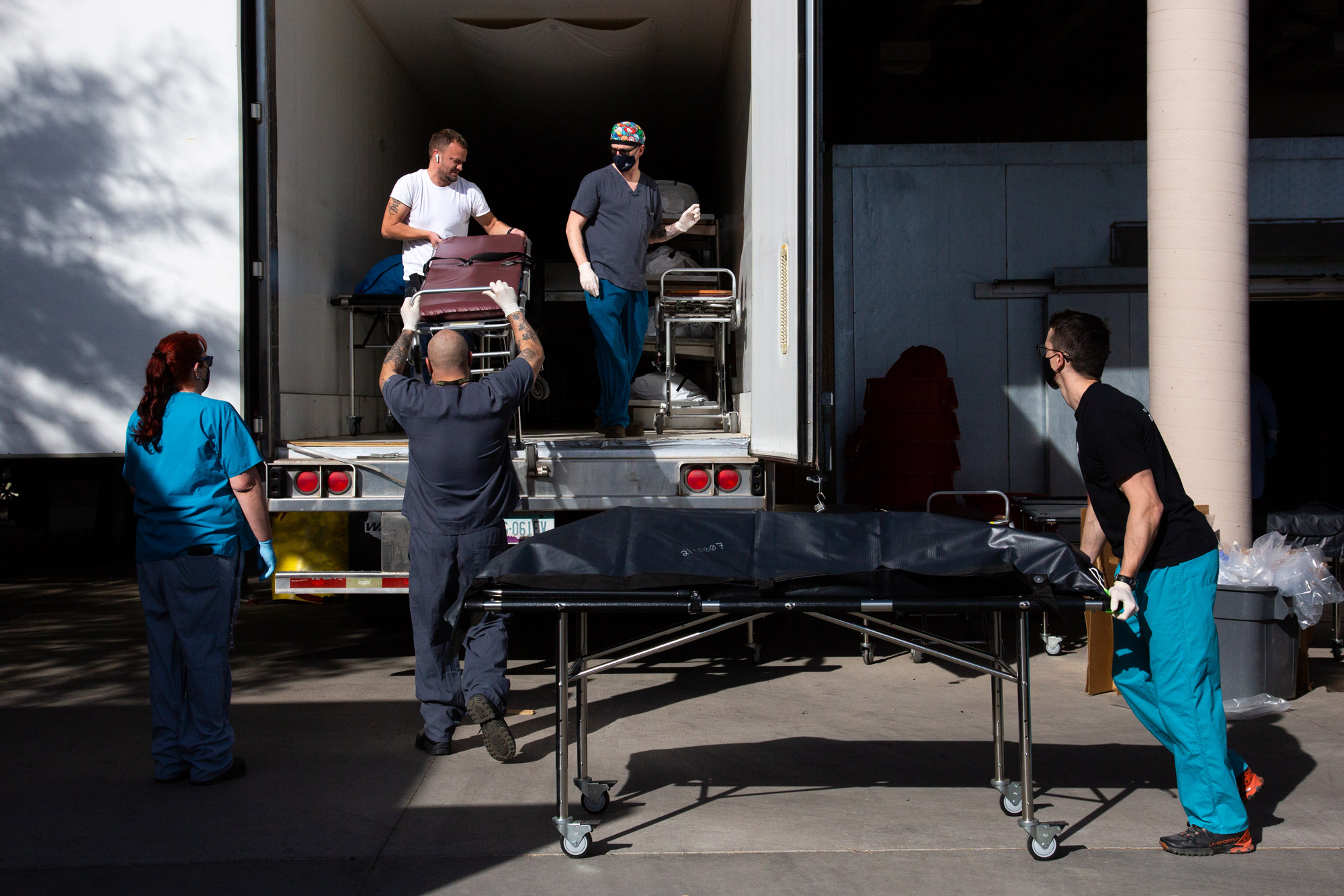 Employees move bodies into refrigerated semi-trucks at the Pima County Office of the Medical Examiner on January 14 in Tucson, Arizona. 