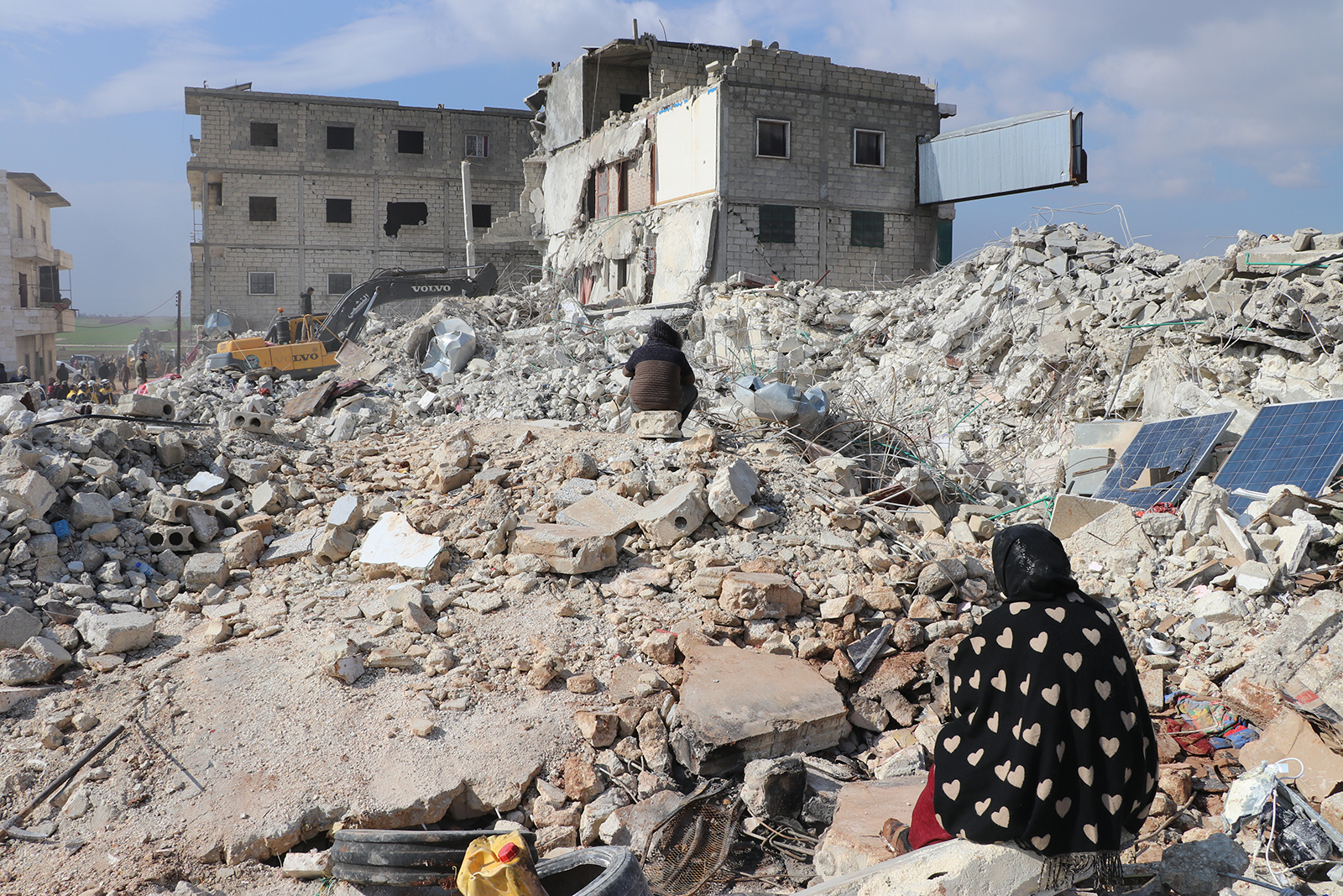 A woman sits near the rubble of destroyed buildings in the city of Atarib, in the western countryside of Aleppo.