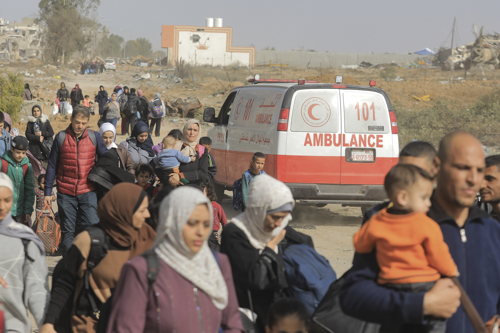 Palestinians pass by a Red Crescent ambulance in Gaza on November 26.
