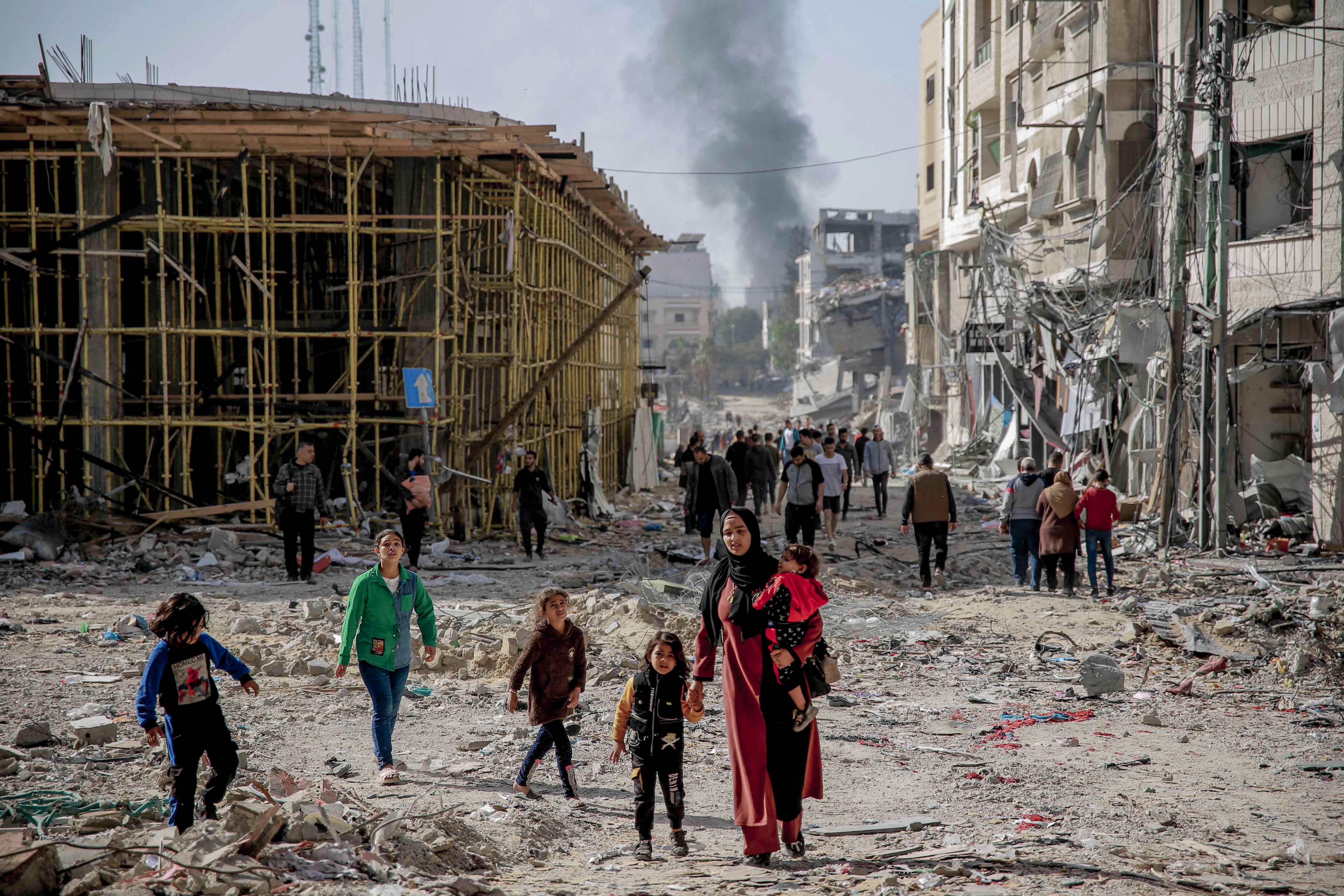 Palestinians walk amid the rubble of destroyed buildings in Gaza City following weeks of Israeli bombardment, as a four-day ceasefire took effect, on November 24, 2023.